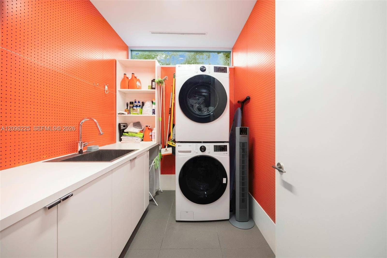 Laundry area featuring perforated metal wall panels, built-in white cabinetry, a deep rectangular sink with a gooseneck faucet, and tile flooring