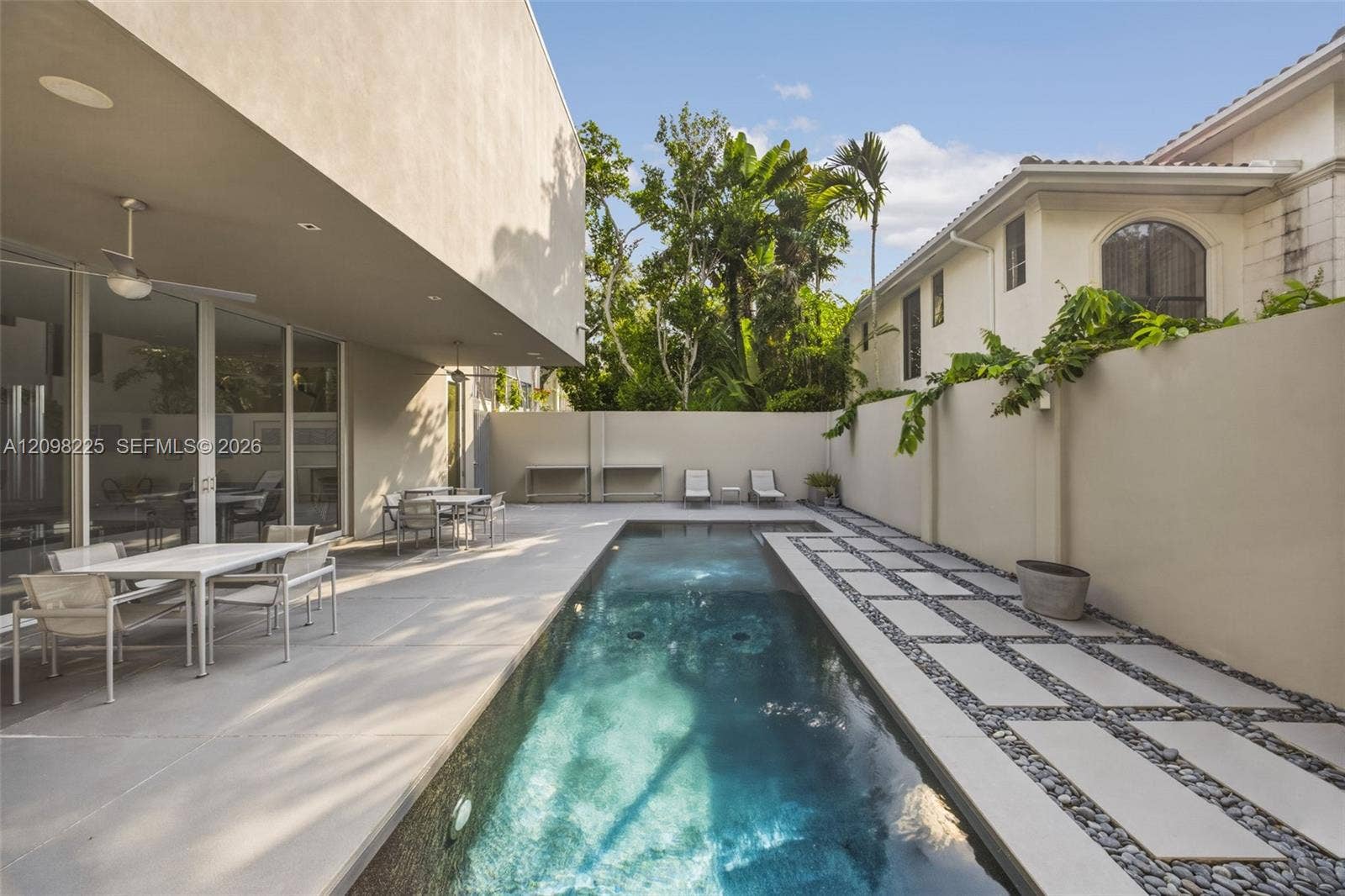 Private patio featuring an in-ground lap pool, concrete hardscaping, a raised perimeter wall, and built-in recessed lighting