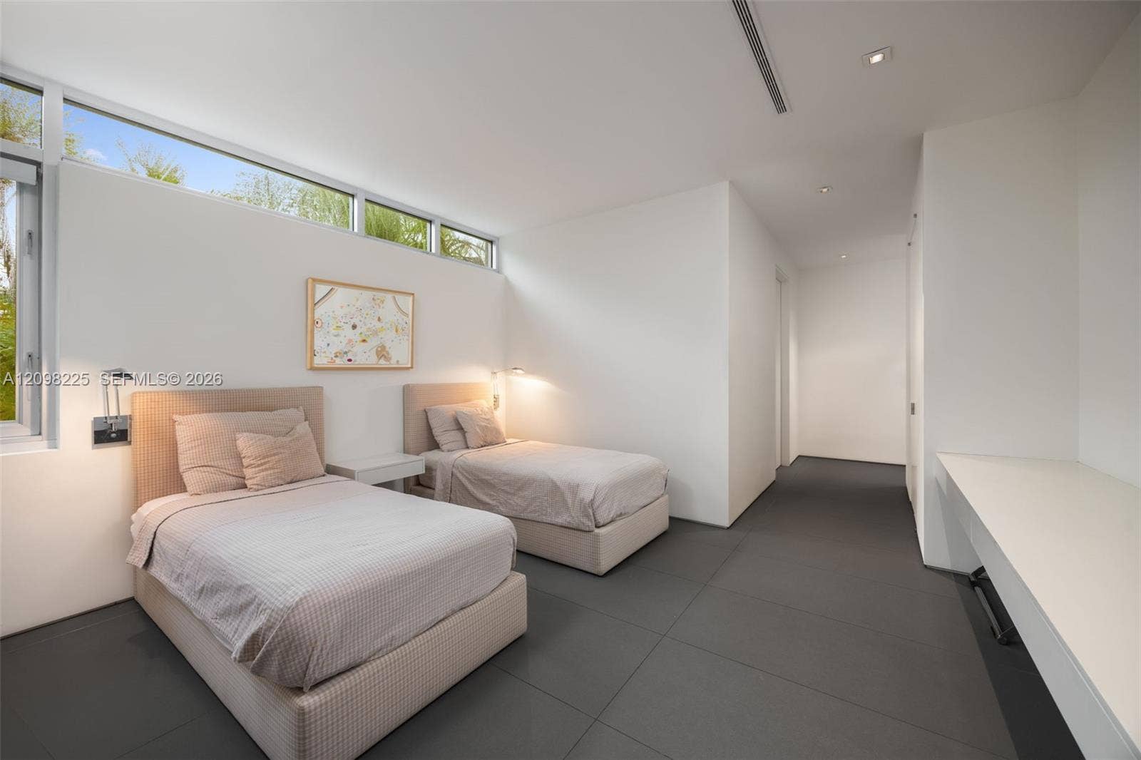 Minimalist room featuring large-format dark grey tile flooring, high-placed clerestory windows, a built-in white desk, and recessed ceiling lighting