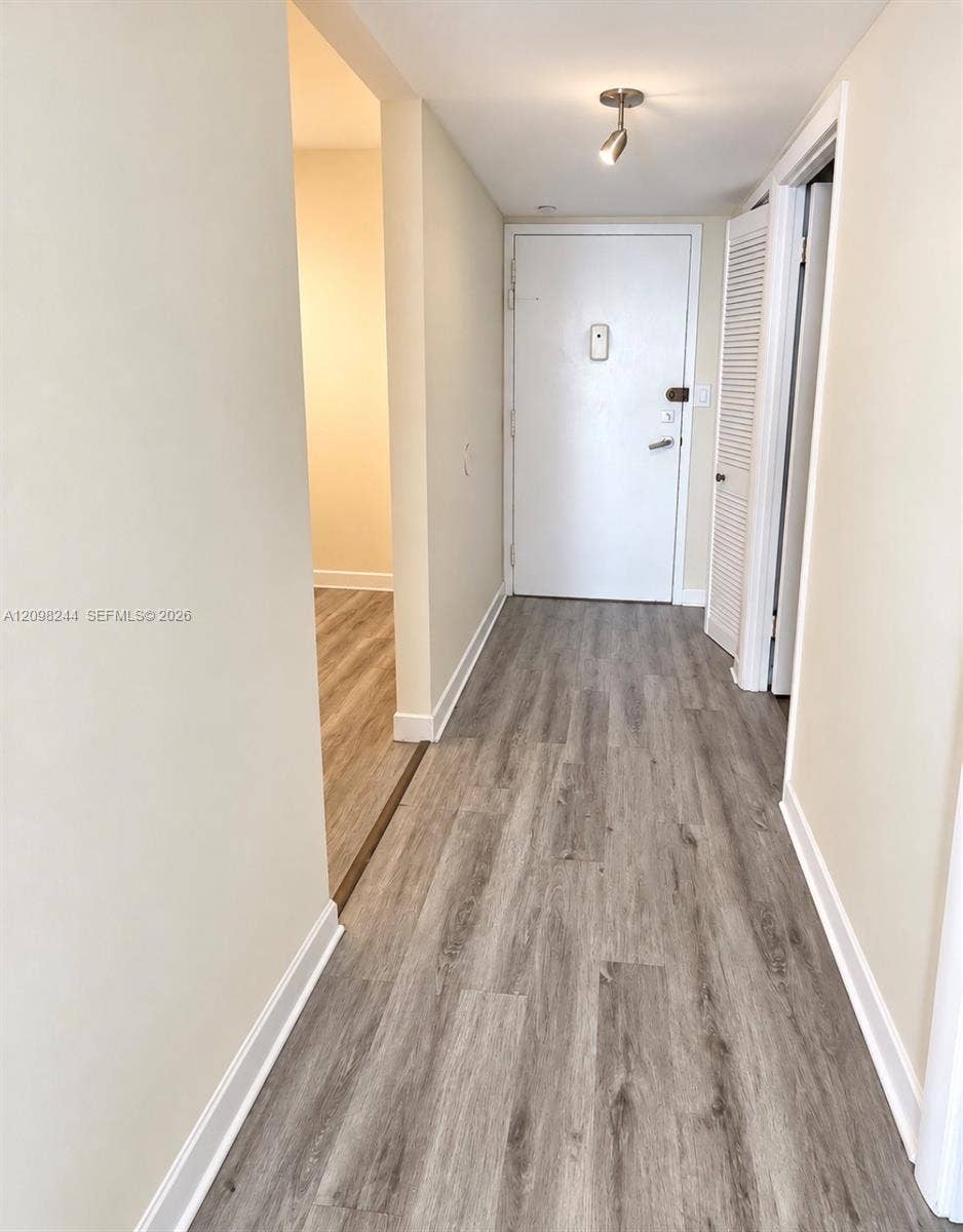 2851 NE 183rd Street, #2110E, Aventura, Aventura, FL 33160 Entryway featuring wood-finish flooring, neutral wall paint, a single-bulb directional ceiling light, and a white louvered closet door