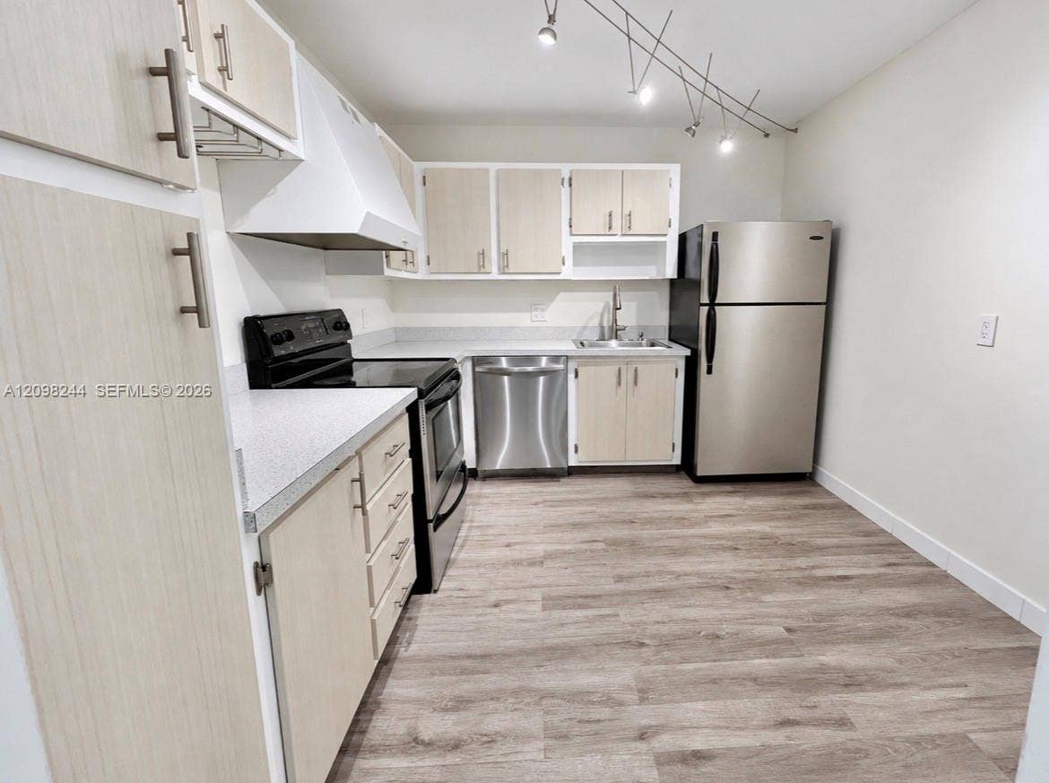 2851 NE 183rd Street, #2110E, Aventura, Aventura, FL 33160 Kitchen featuring light wood-finish cabinetry, stainless steel appliances, solid surface countertops, track lighting, and wood-finish flooring