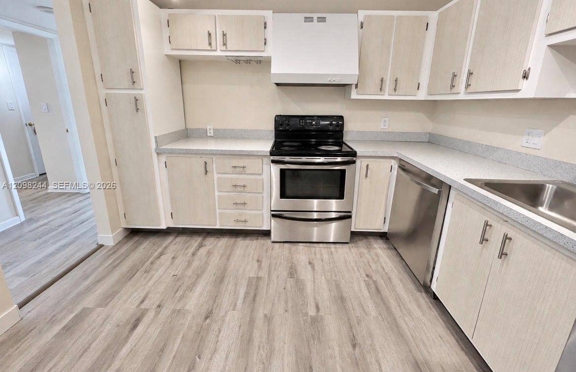 2851 NE 183rd Street, #2110E, Aventura, Aventura, FL 33160 Kitchen featuring light-finish cabinetry, neutral solid-surface countertops, stainless steel appliances, and wood-finish flooring