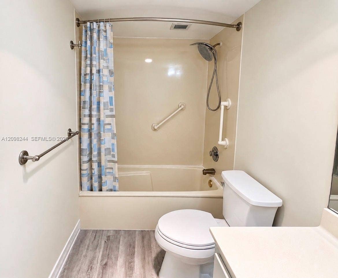 2851 NE 183rd Street, #2110E, Aventura, Aventura, FL 33160 Bathroom featuring wood-finish flooring, a combination tub and shower enclosure with a handheld spray fixture, and neutral wall-mounted grab bars