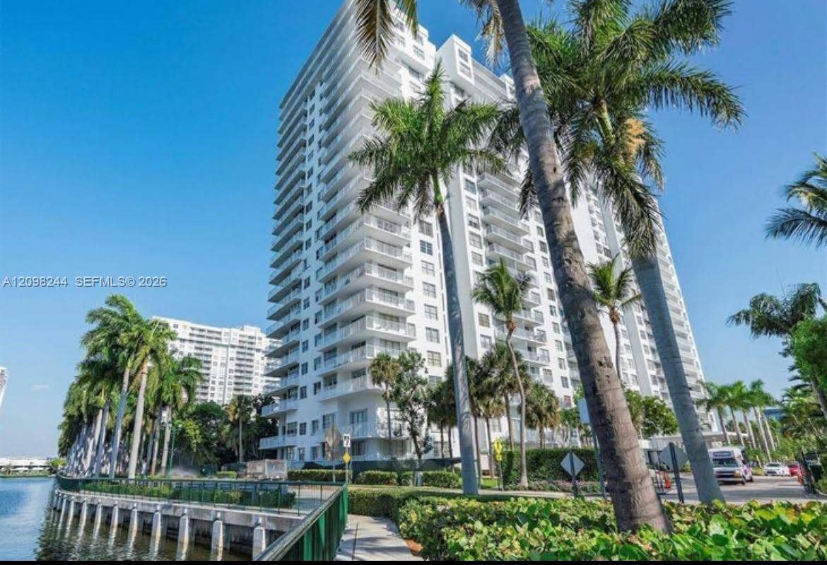 2851 NE 183rd Street, #2110E, Aventura, Aventura, FL 33160 High-rise residential exterior featuring stacked private balconies, glass railings, white concrete facade, and mature palm tree landscaping