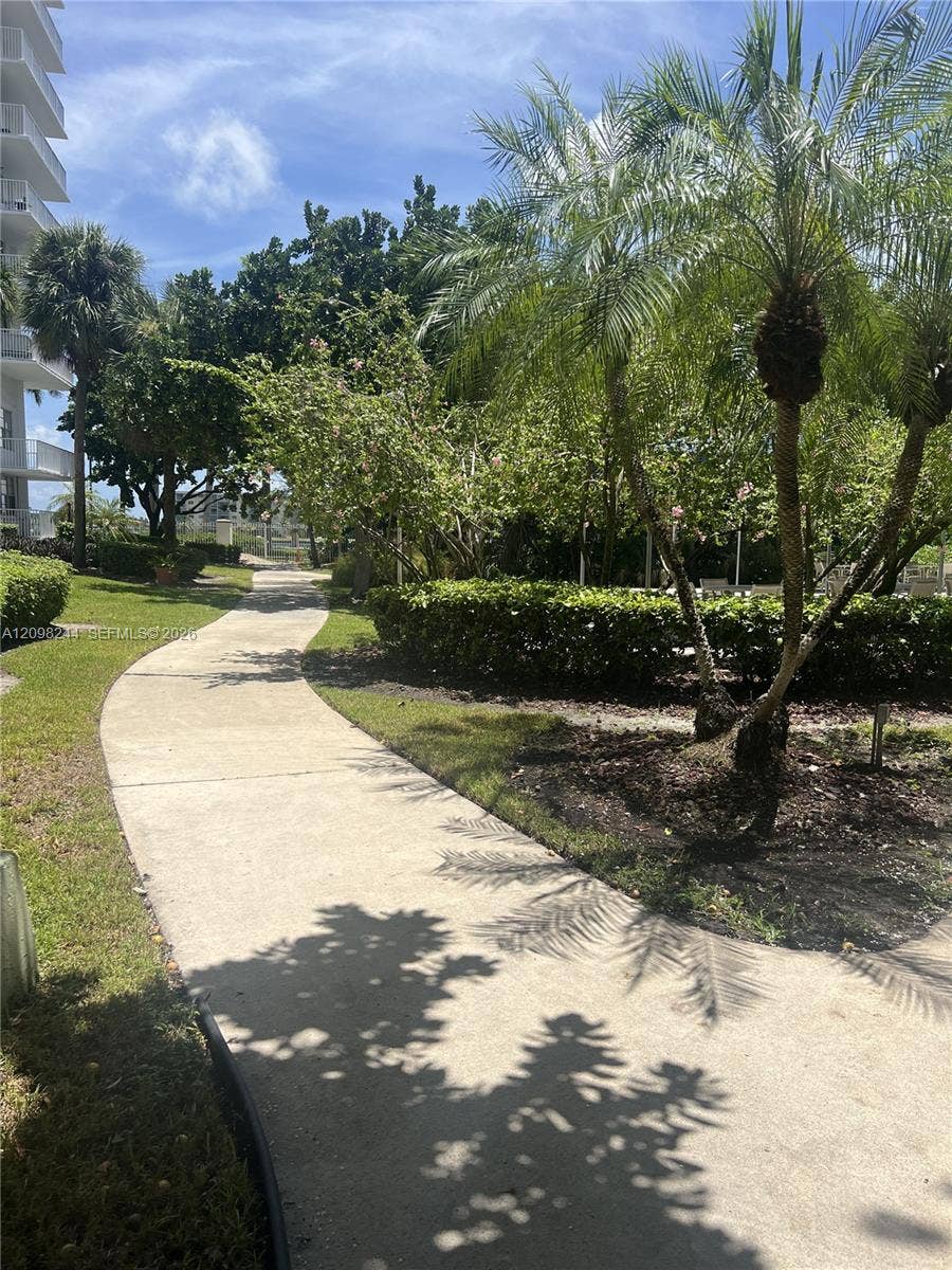 2851 NE 183rd Street, #2110E, Aventura, Aventura, FL 33160 Concrete walking path winding through grounds with manicured hedges and mature palm trees