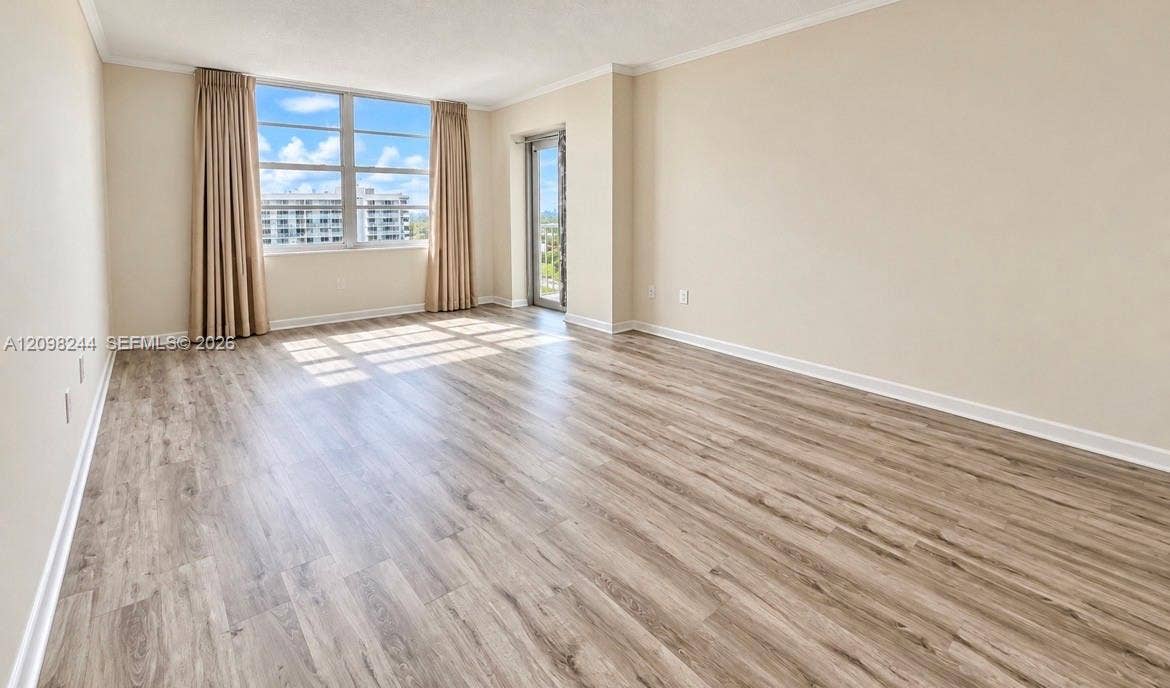 2851 NE 183rd Street, #2110E, Aventura, Aventura, FL 33160 Neutral-toned interior featuring wood-finish flooring, expansive floor-to-ceiling windows, crown molding, and a glass-paneled door