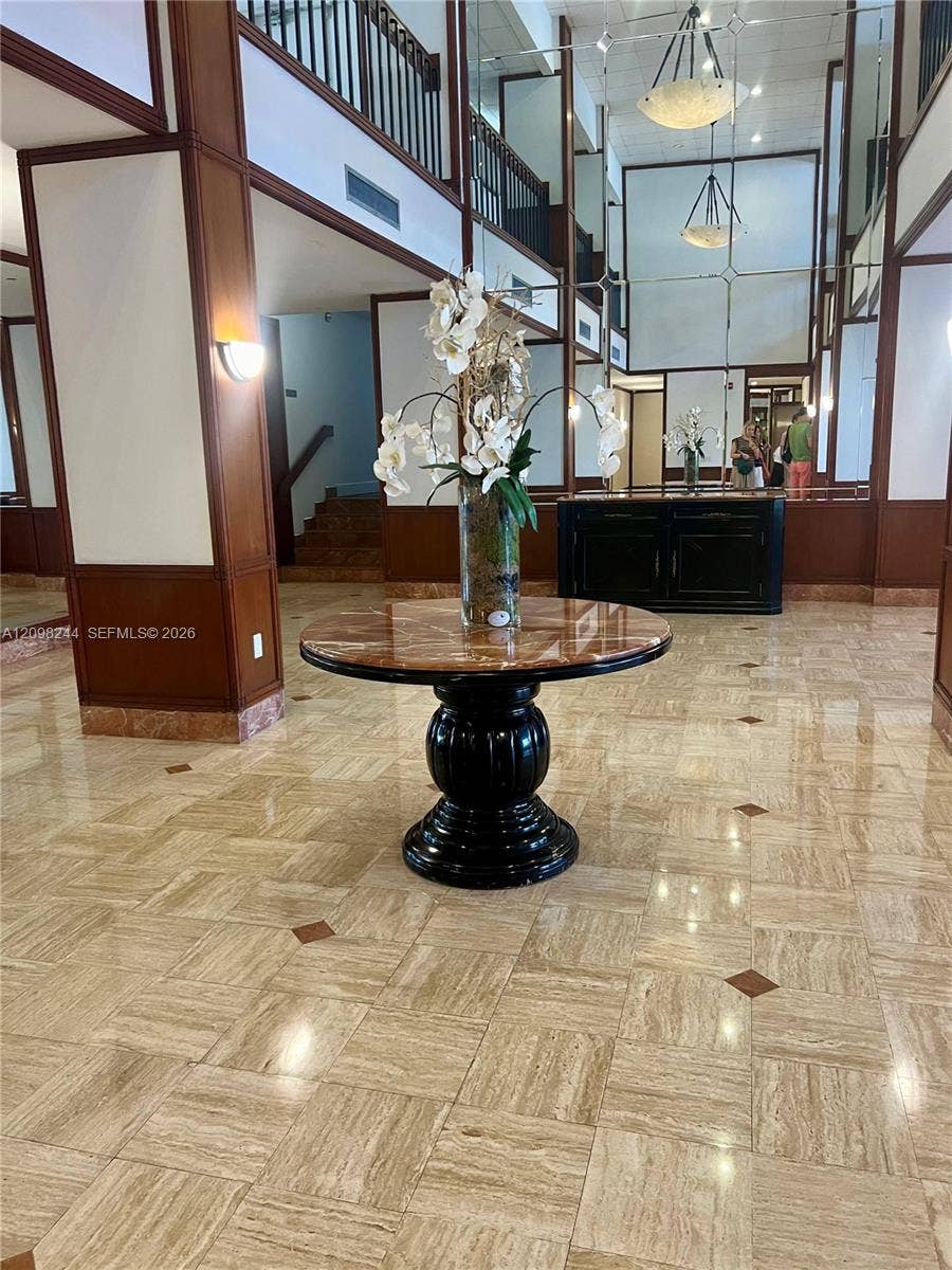 2851 NE 183rd Street, #2110E, Aventura, Aventura, FL 33160 Grand foyer featuring high-gloss stone tile flooring with decorative inlay, two-story ceiling height, full-height wall mirrors, and wood-paneled columns