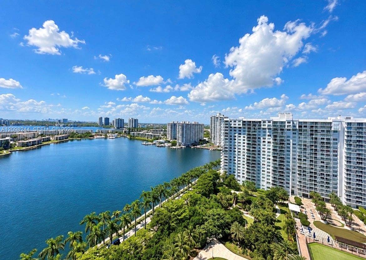 2851 NE 183rd Street, #2110E, Aventura, Aventura, FL 33160 High-rise balcony perspective featuring expansive water frontage, mature palm trees, landscaped grounds, and a paved walkway