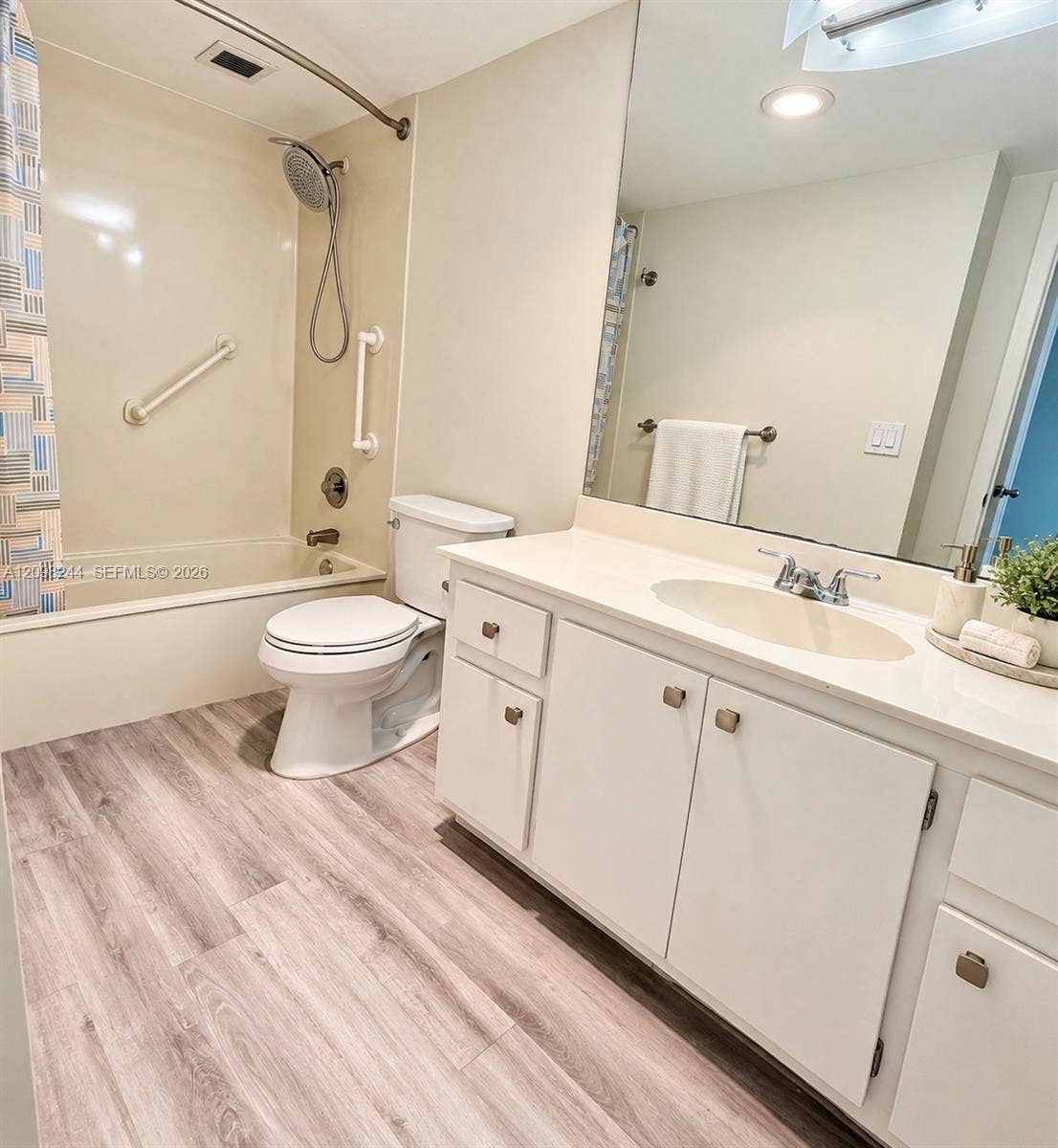 2851 NE 183rd Street, #2110E, Aventura, Aventura, FL 33160 Bathroom featuring a large vanity with a solid-surface countertop, integrated basin, wood-finish flooring, and a shower-tub combination with wall-mounted grab bars and a handheld fixture
