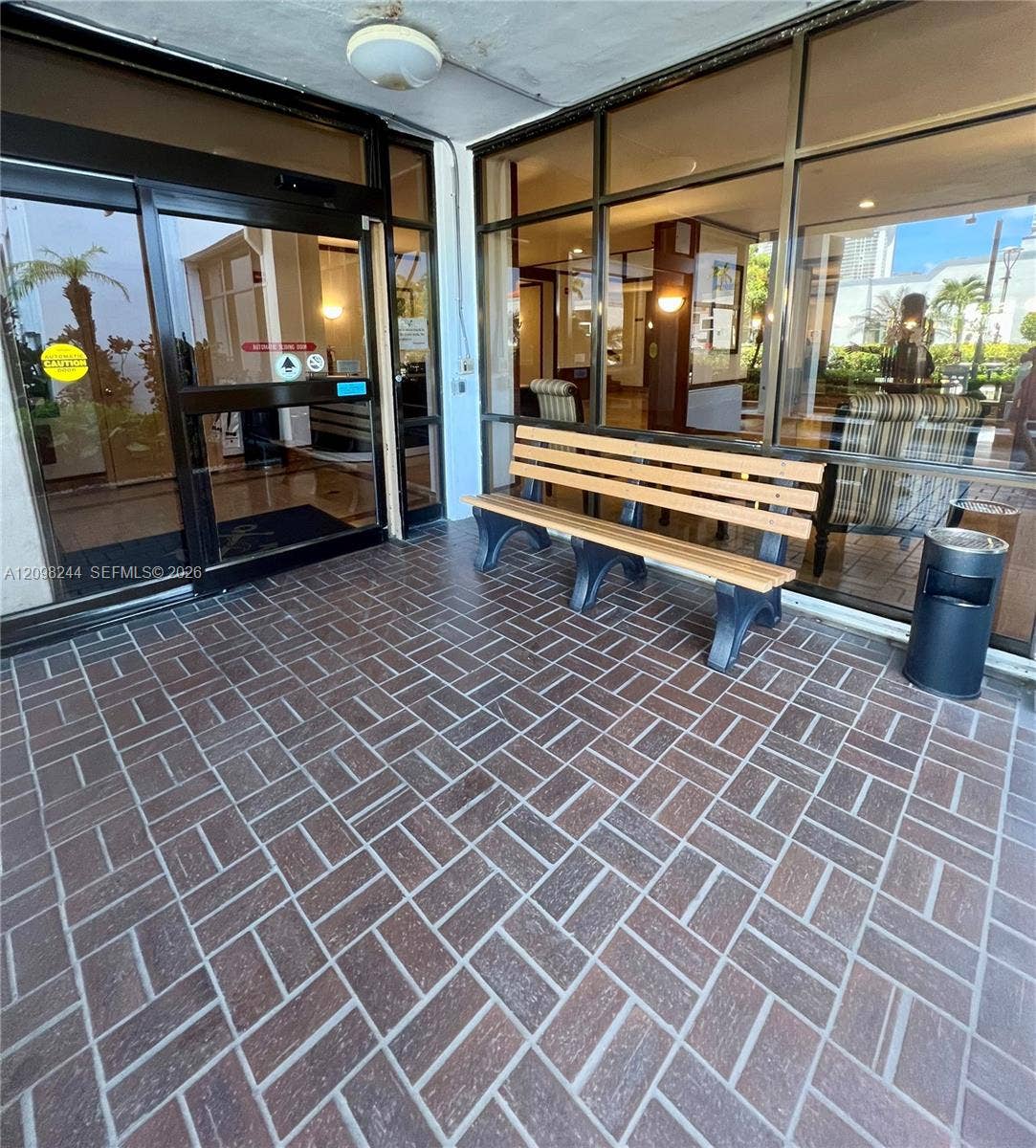 2851 NE 183rd Street, #2110E, Aventura, Aventura, FL 33160 Covered building entrance featuring a herringbone-patterned tile floor, expansive floor-to-ceiling glass wall, and aluminum-framed sliding glass doors