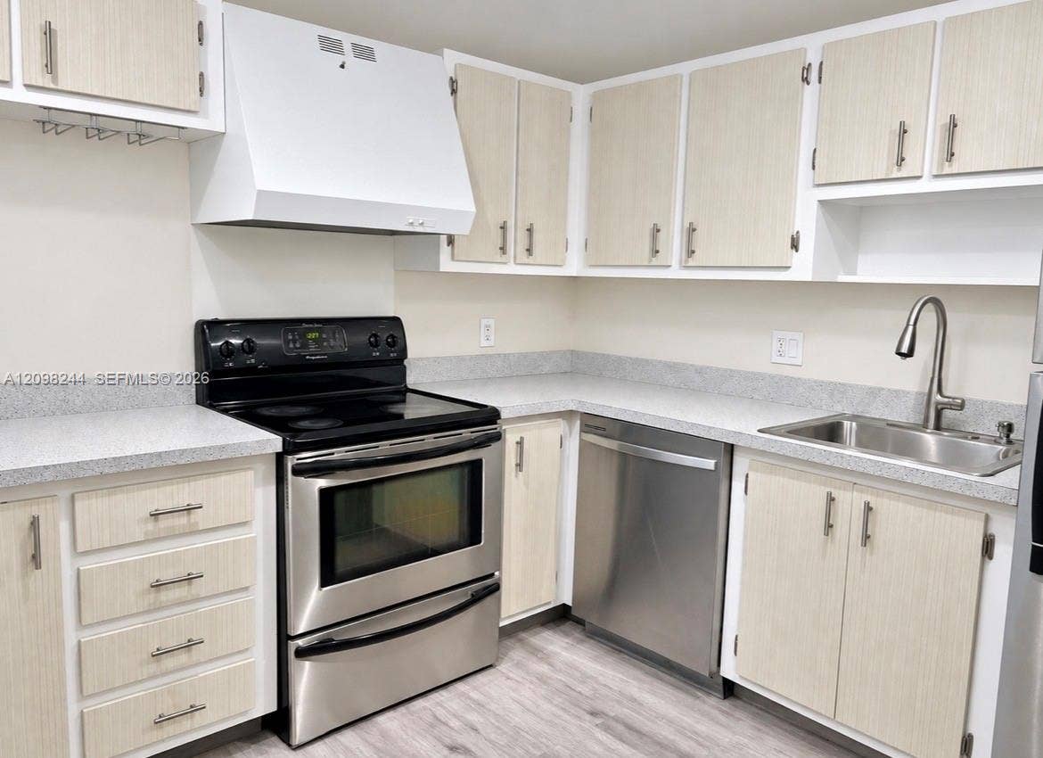 2851 NE 183rd Street, #2110E, Aventura, Aventura, FL 33160 Kitchen featuring light-finish cabinetry, stainless steel appliances, speckled stone-composite countertops, stainless steel undermount sink with gooseneck faucet, and wood-finish flooring