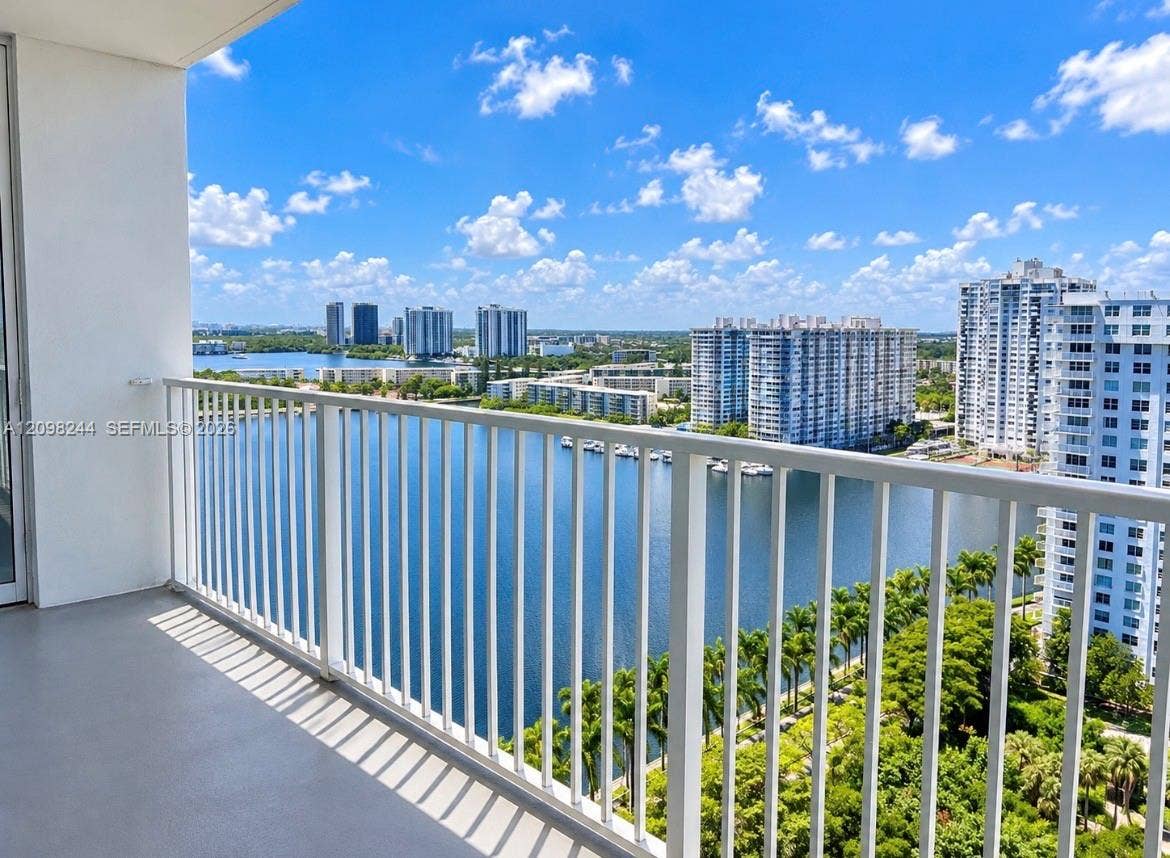 2851 NE 183rd Street, #2110E, Aventura, Aventura, FL 33160 Covered balcony featuring white vertical railings, concrete flooring, and an expanse overlooking a waterfront and high-rise skyline