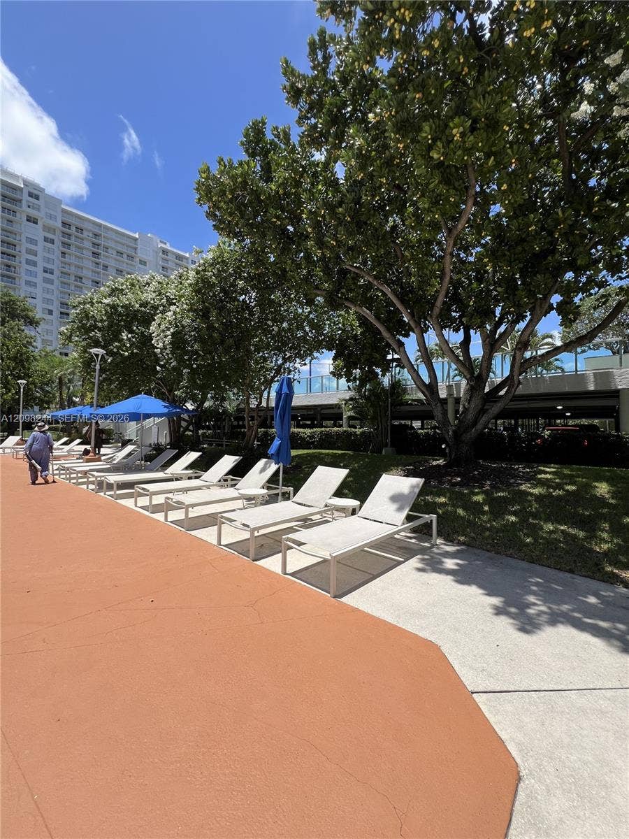 2851 NE 183rd Street, #2110E, Aventura, Aventura, FL 33160 Outdoor pool deck featuring expansive concrete surfacing, mature landscaping, and multi-level parking structure