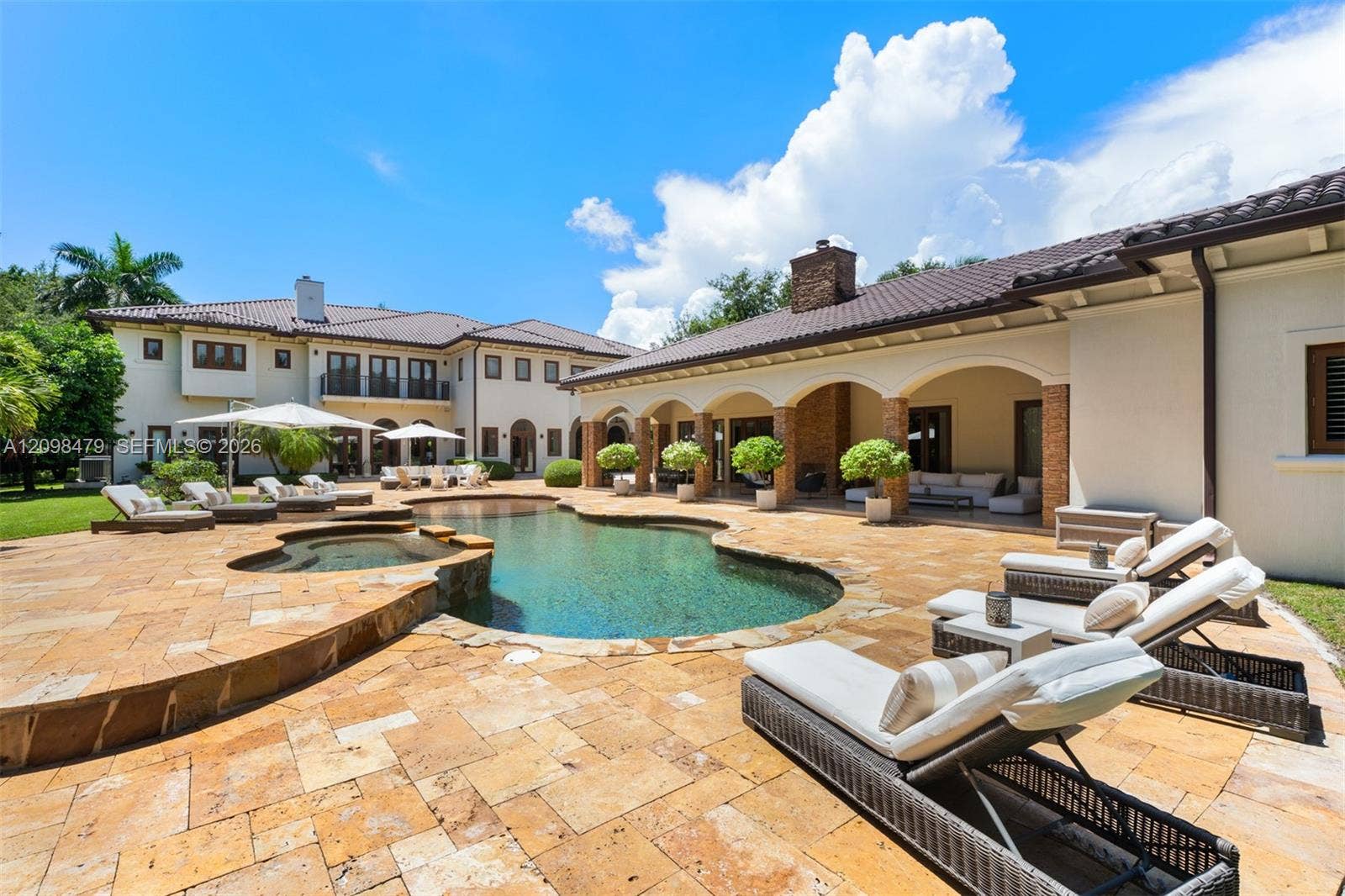 Resort-style backyard featuring a freeform swimming pool, integrated spa, and expansive paver patio