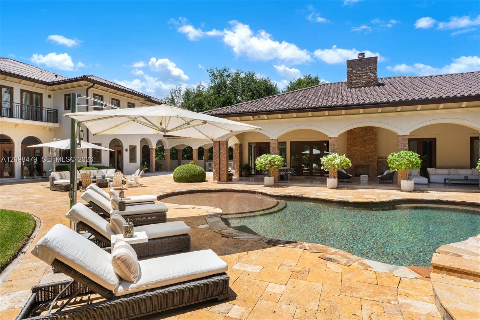 Expansive outdoor living area featuring a freeform swimming pool, integrated spa, and extensive paver patio