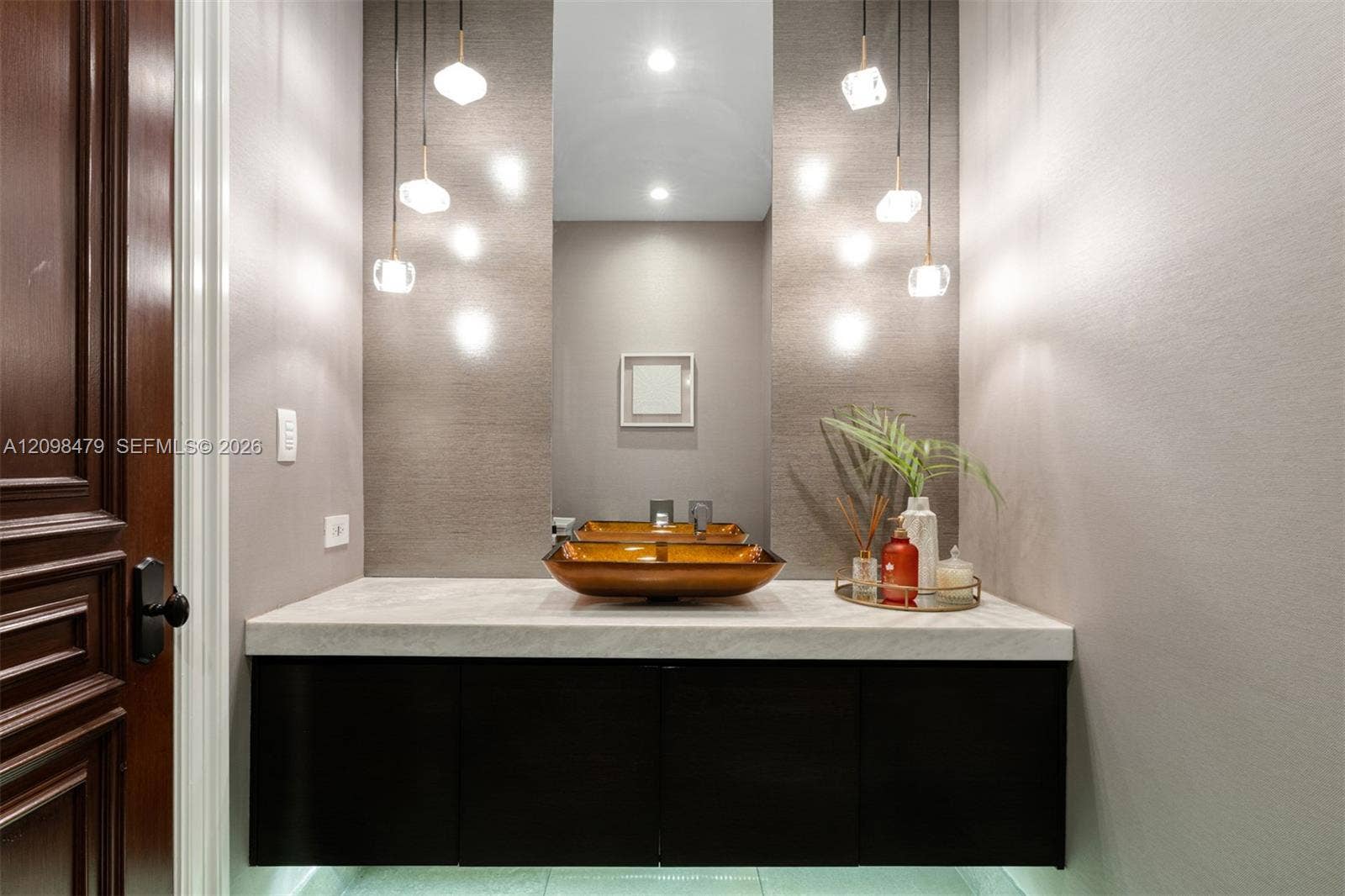 Floating vanity with a light-toned countertop, under-cabinet lighting, and a vessel sink
