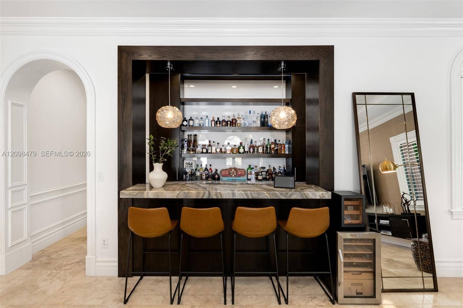 Built-in wet bar with a dark wood finish and stone countertop, illuminated by two pendant light fixtures