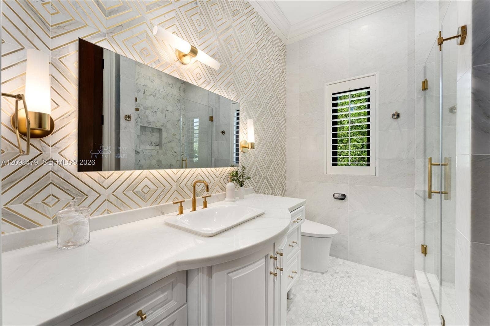 Custom vanity with a curved countertop, integrated sink, and gold-finish fixtures