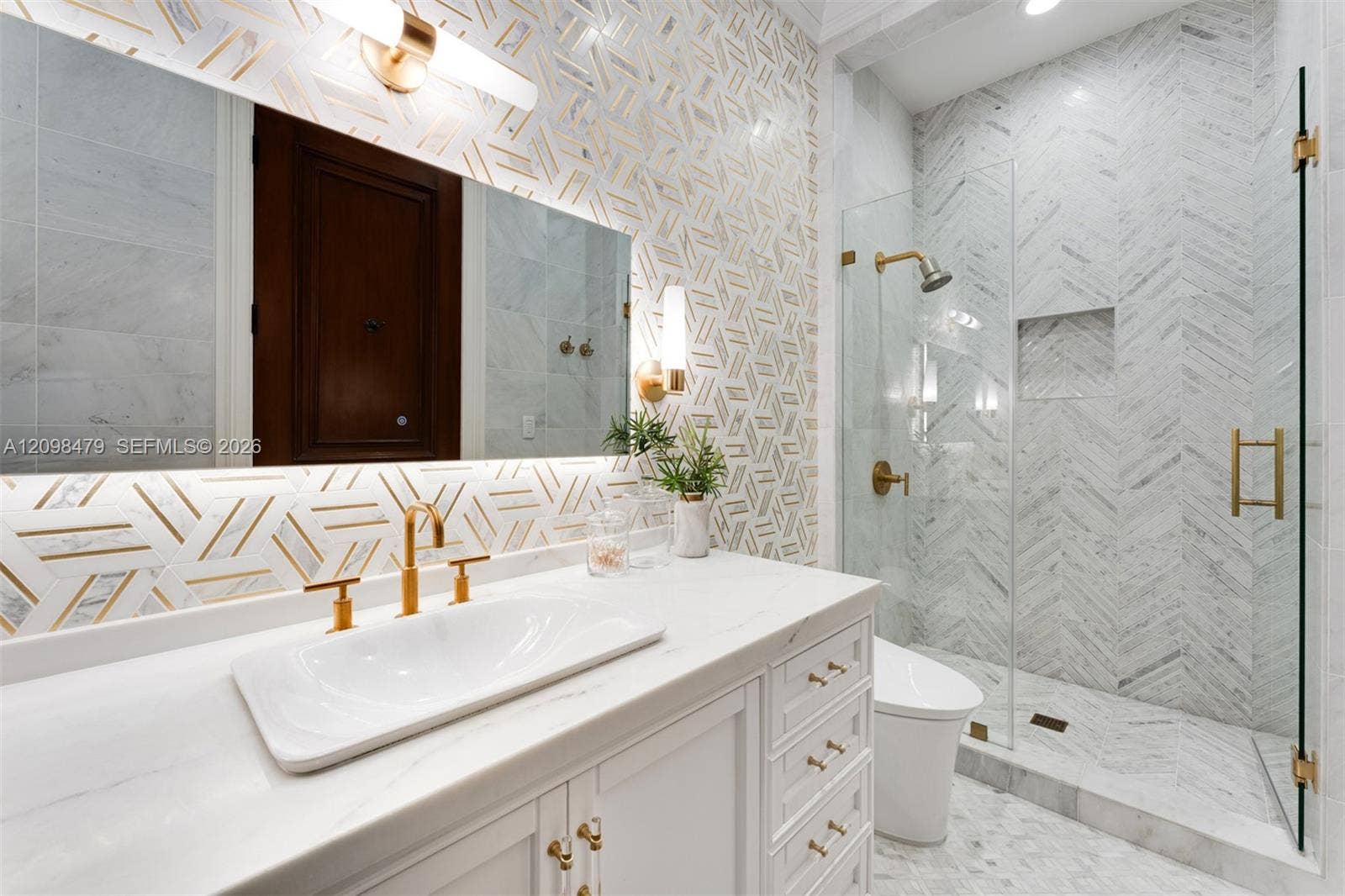 White vanity with gold hardware, a rectangular vessel sink, and gold-finish faucet