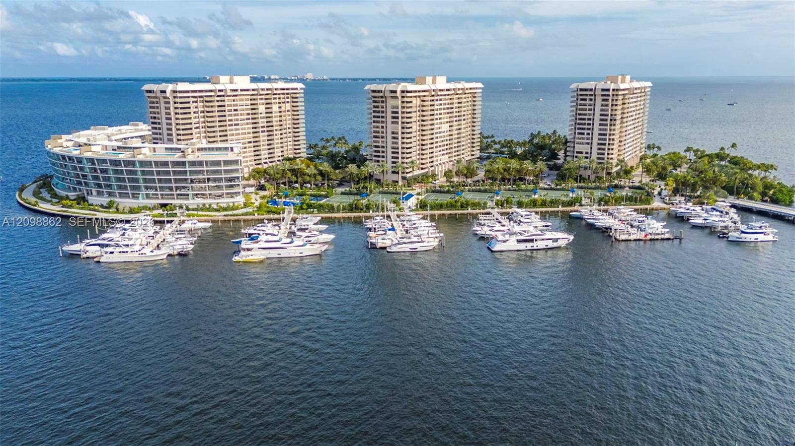 Waterfront high-rise complex featuring private deep-water boat slips, tennis courts, landscaped grounds, and paved walkways