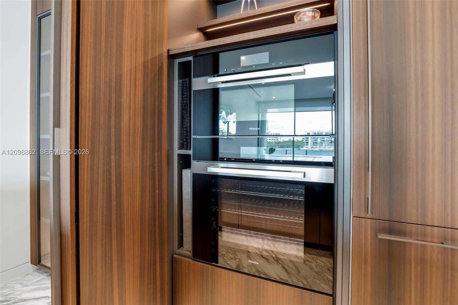 Built-in stainless steel double wall ovens, wood-finish cabinetry, integrated task lighting, and open shelving
