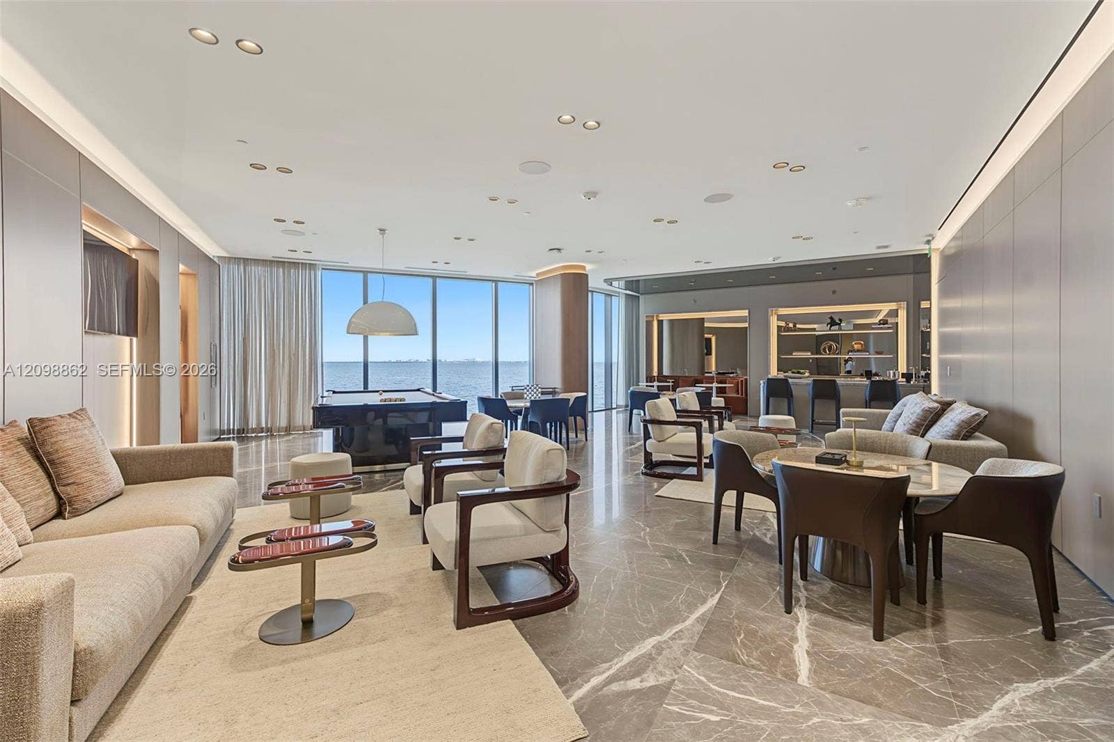 Floor-to-ceiling glass windows featuring water scenery, polished stone flooring, recessed ceiling lighting, and integrated wall paneling