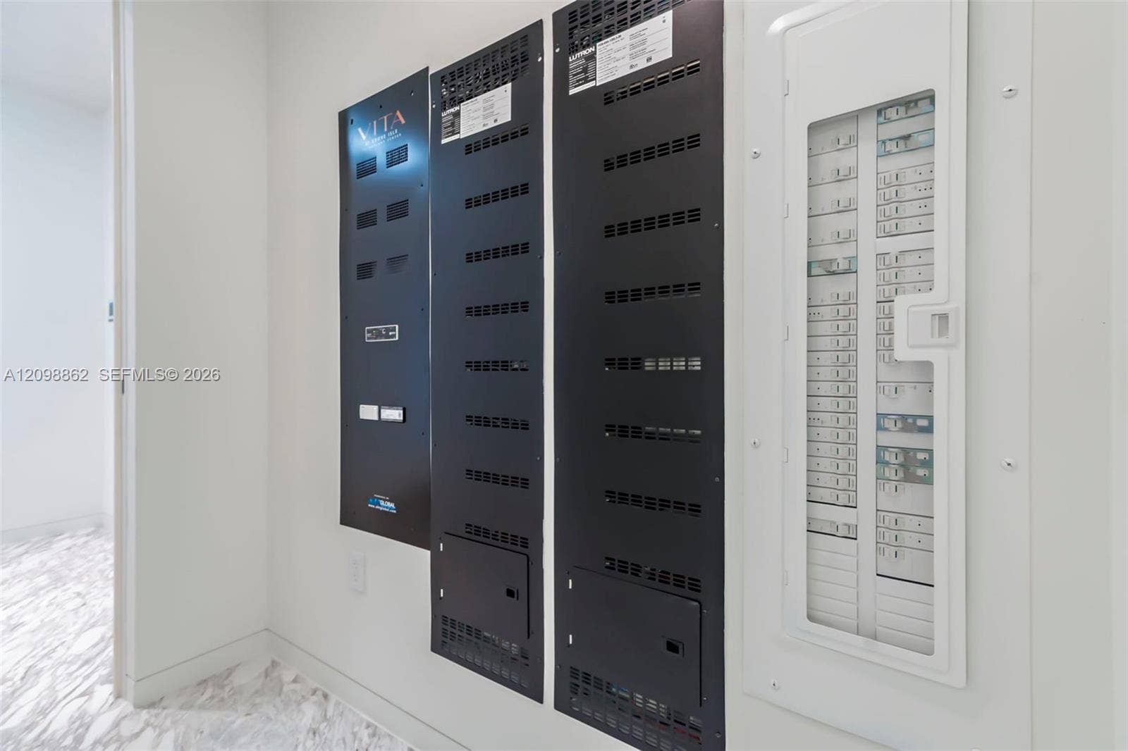 Wall-mounted electrical service panels with integrated black metal vented covers and a white-framed circuit breaker enclosure