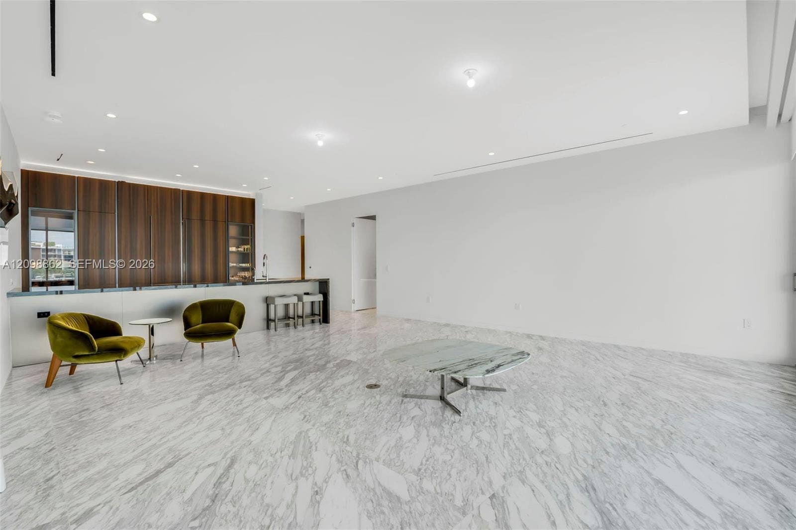 Polished stone flooring, custom wood-veneer cabinetry, recessed ceiling lighting, and a built-in bar counter