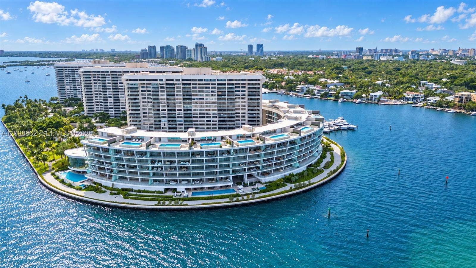 Waterfront high-rise complex situated on a peninsula, featuring multiple tiered balconies, private terrace swimming pools, and extensive perimeter landscaping