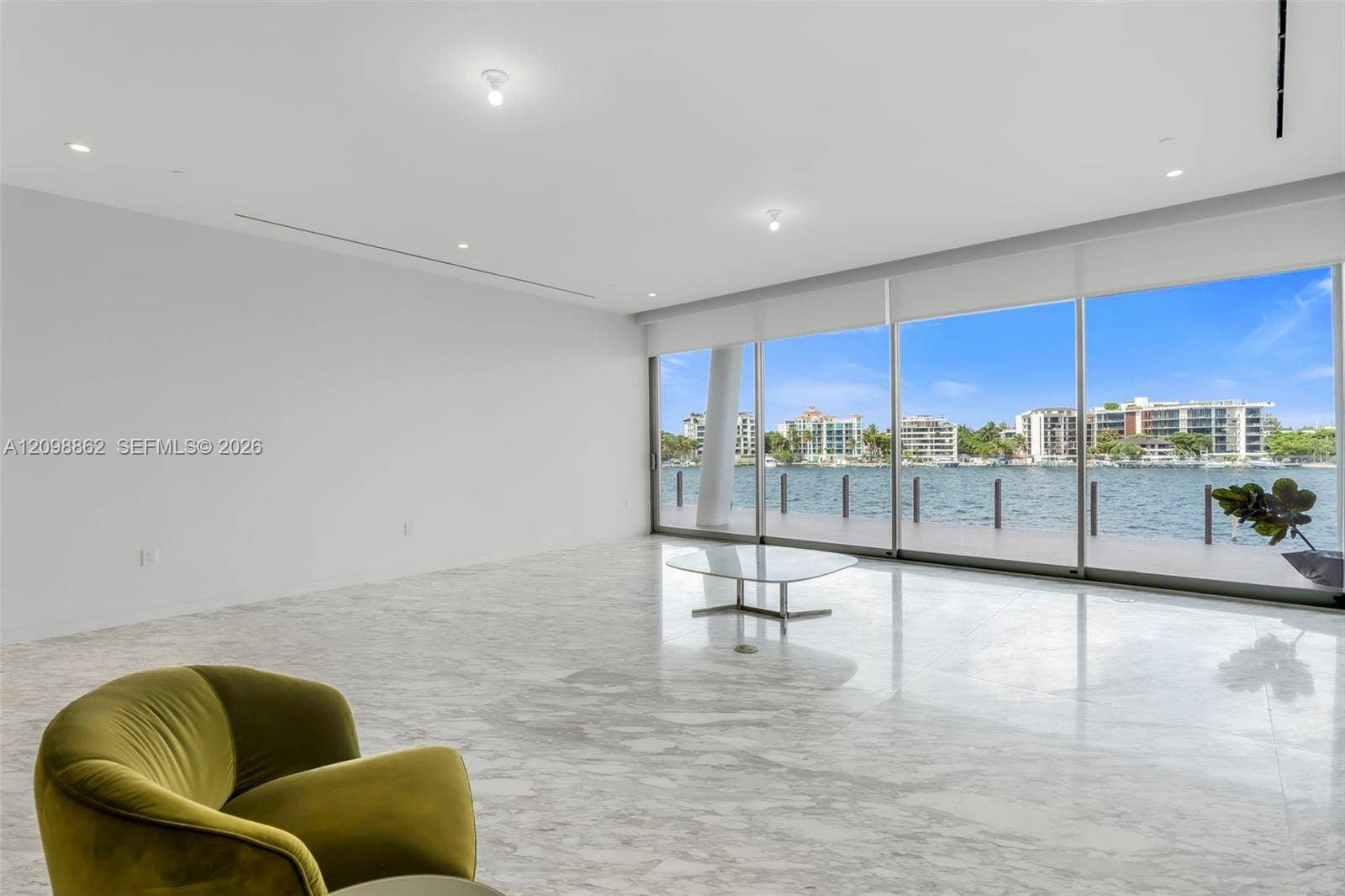 Floor-to-ceiling glass wall panels, polished stone flooring, recessed ceiling lighting, and waterfront balcony access