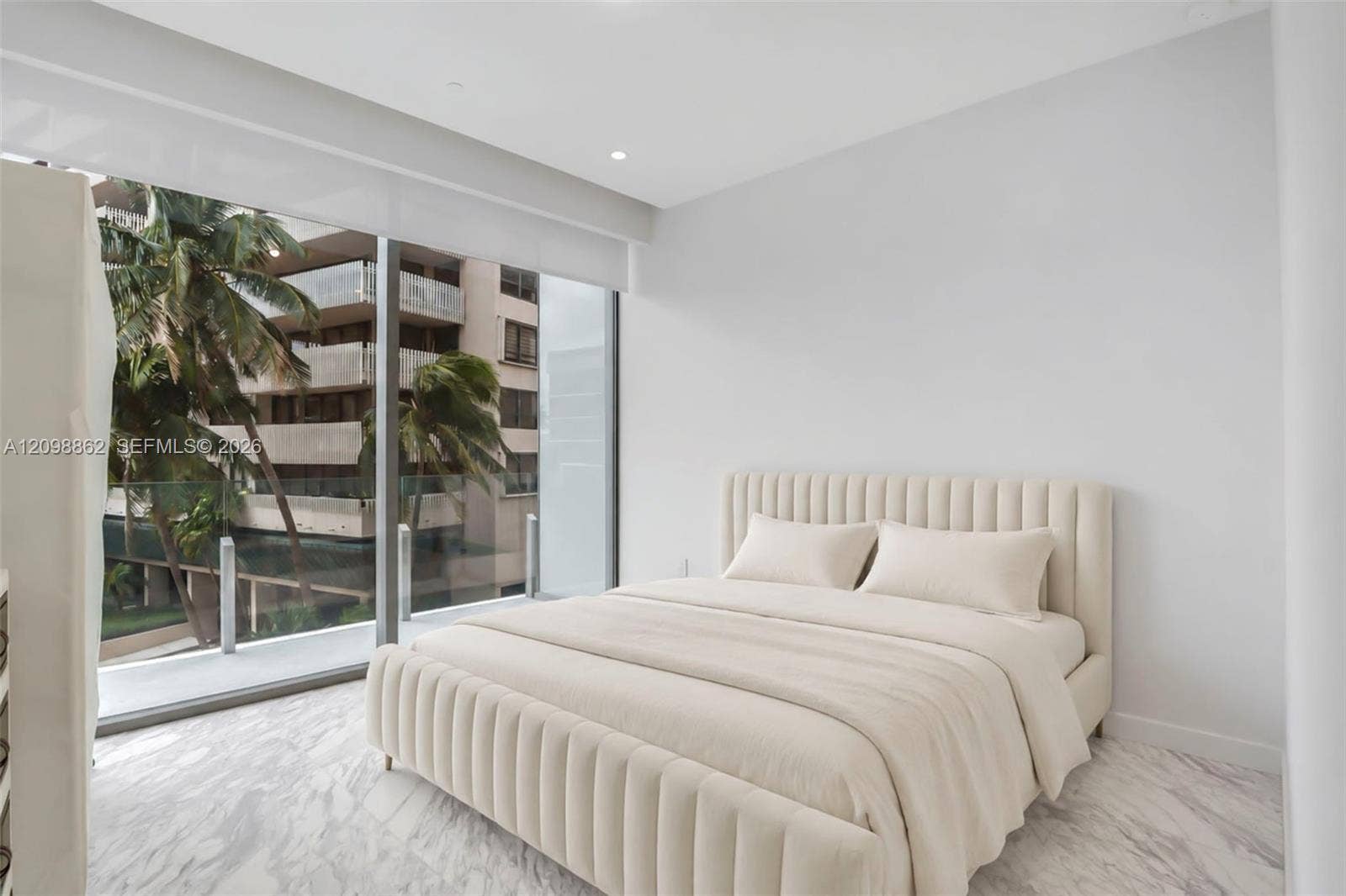Floor-to-ceiling glass sliding doors, private balcony with metal railing, stone-finish flooring, and recessed ceiling lighting
