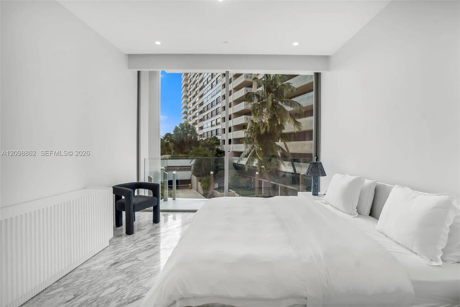 Full-height glass sliding doors, stone flooring, recessed ceiling lighting, and a glass-railed balcony