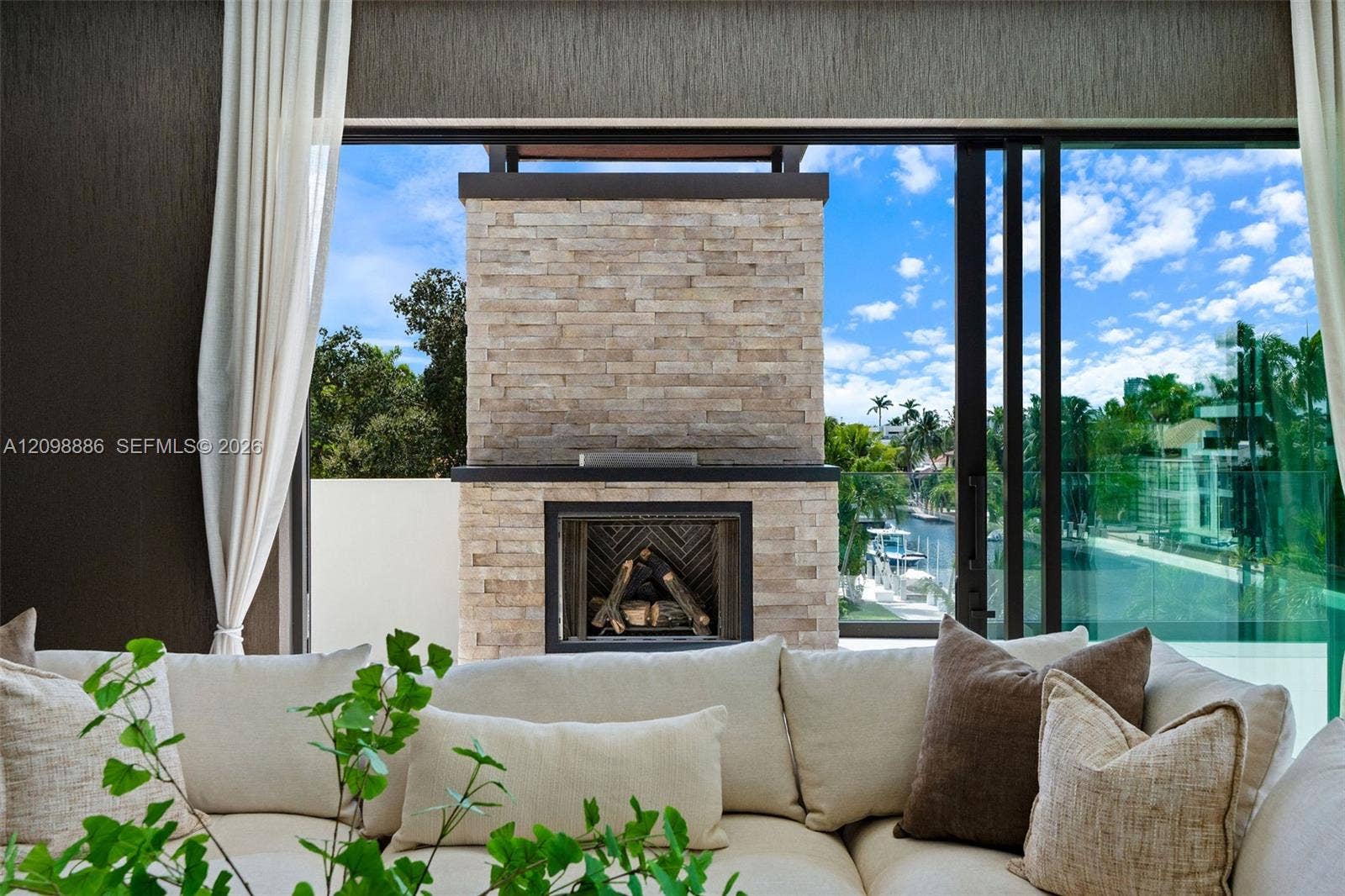 Stone-clad exterior fireplace, expansive sliding glass wall system, and glass panel balcony railing
