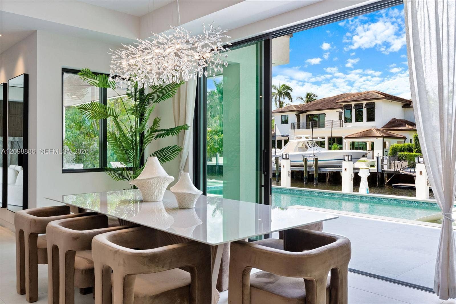 Multi-panel sliding glass doors, contemporary crystal chandelier, built-in swimming pool, deep-water dockage, and large-format tile flooring