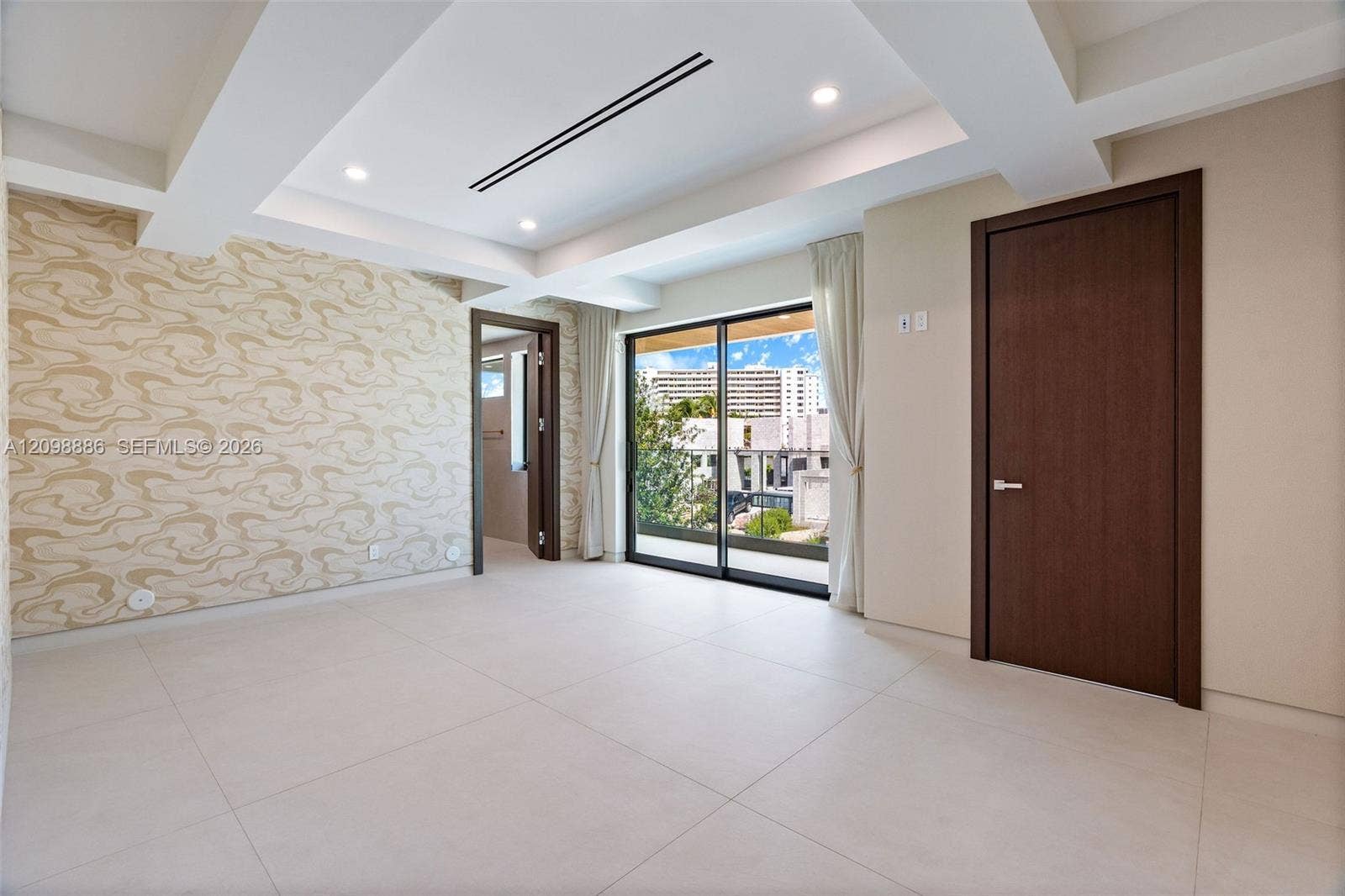 Tray ceiling with recessed lighting, large-format tile flooring, textured wall covering, and sliding glass doors with external access