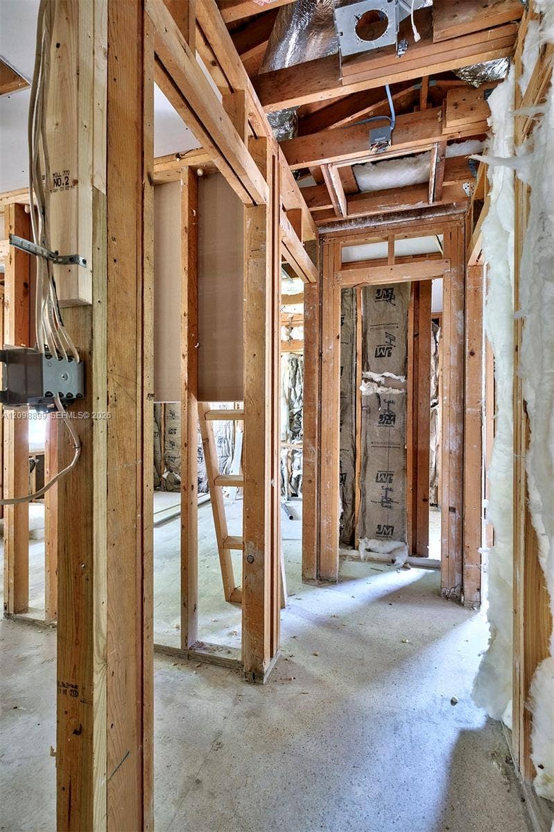 1176 SW 4th Street, Boca Raton, FL 33486 Interior structure featuring exposed wooden wall studs, concrete flooring, exposed ceiling rafters, and installed fiberglass insulation