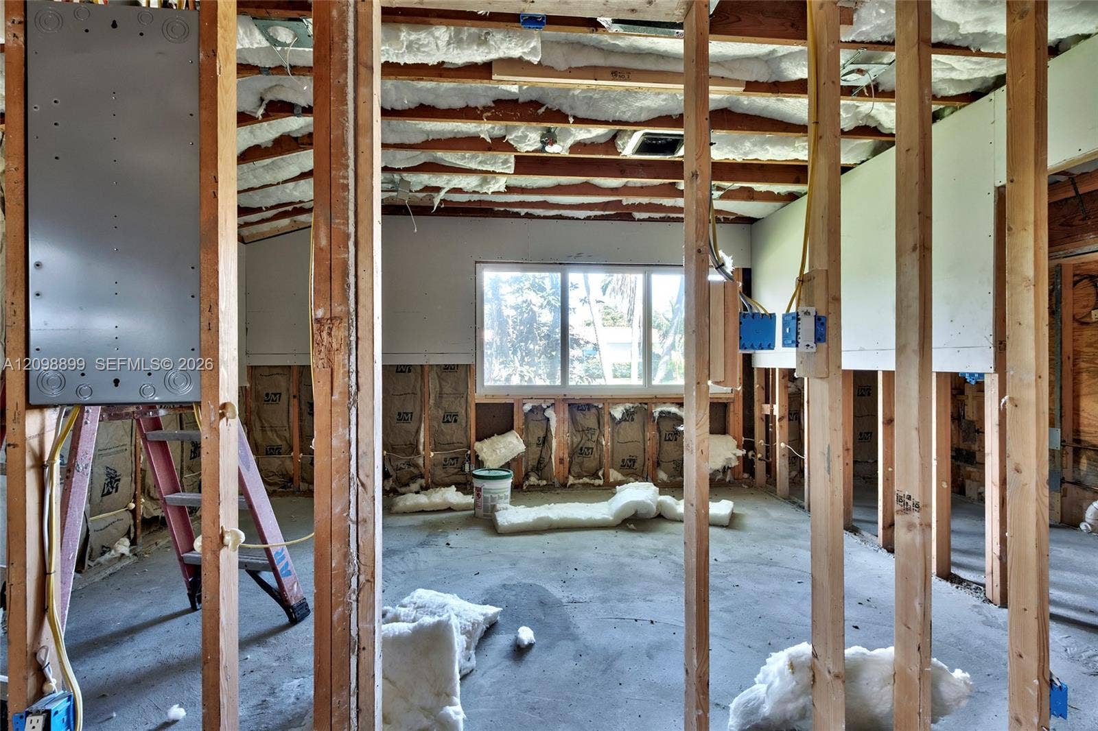 1176 SW 4th Street, Boca Raton, FL 33486 Interior space featuring exposed wood framing, batt insulation, concrete flooring, a multi-pane window, and an installed electrical panel