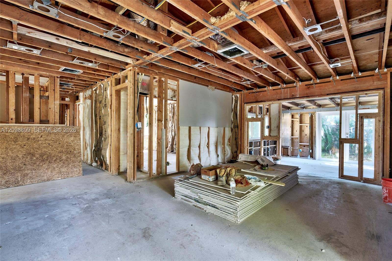 1176 SW 4th Street, Boca Raton, FL 33486 Open-concept interior featuring exposed wood-stud framing, visible ceiling joists, concrete flooring, and large structural openings