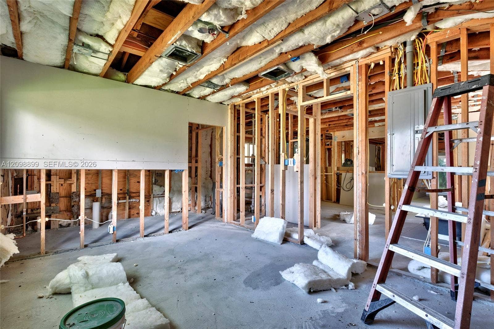 1176 SW 4th Street, Boca Raton, FL 33486 Interior space featuring exposed wood framing, concrete flooring, installed wall insulation, and a mounted electrical service panel