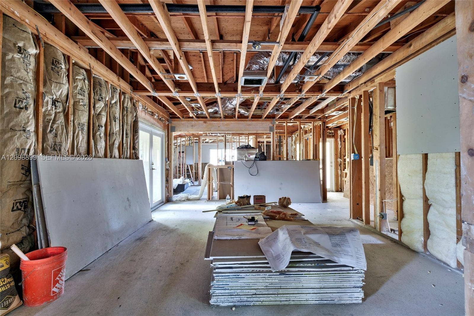 1176 SW 4th Street, Boca Raton, FL 33486 Open-concept interior featuring exposed wood ceiling joists, insulated timber stud walls, and glass panel doors
