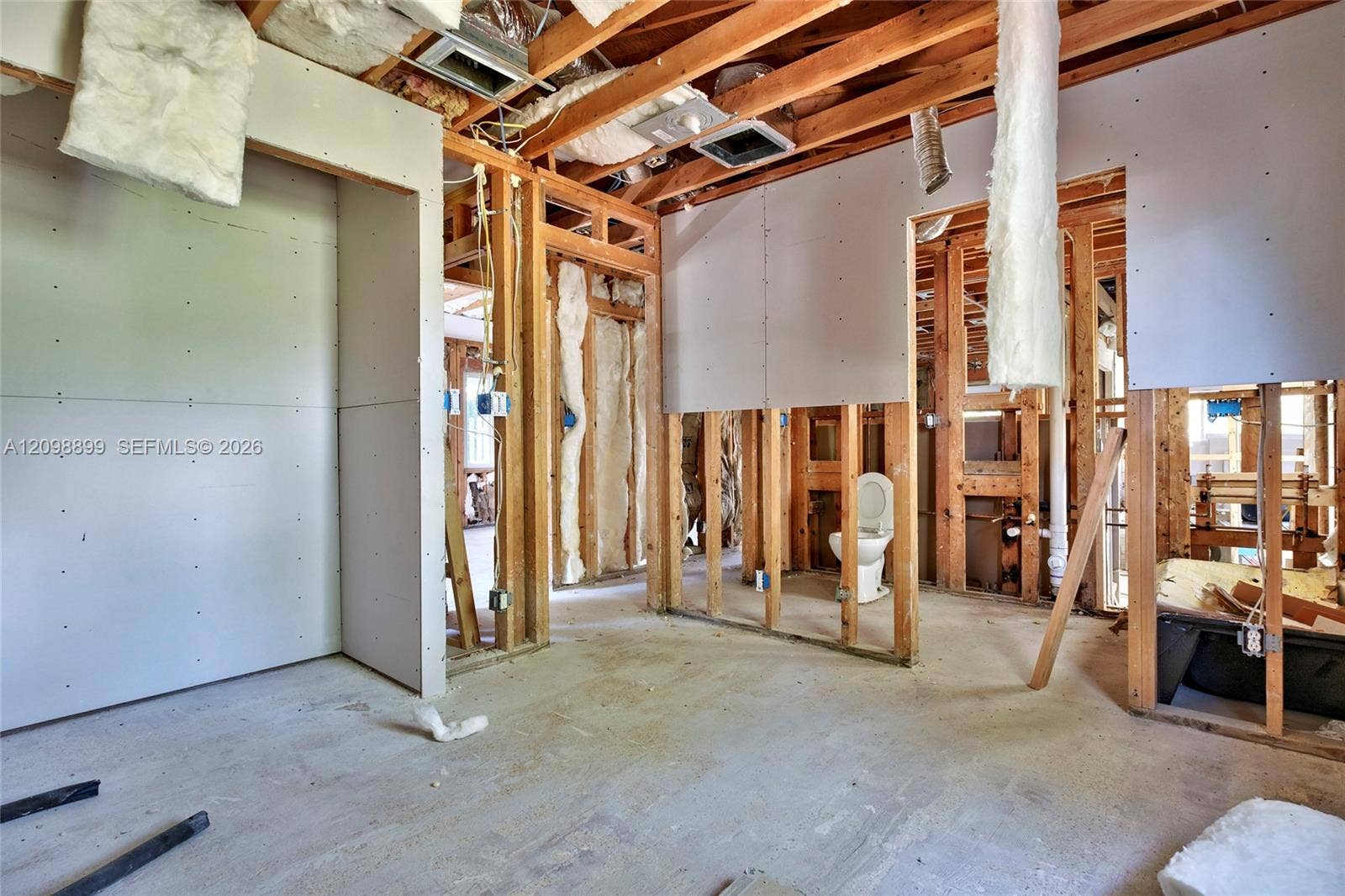 1176 SW 4th Street, Boca Raton, FL 33486 Interior structure featuring exposed wood framing, installed drywall panels, concrete flooring, and an in-place toilet fixture