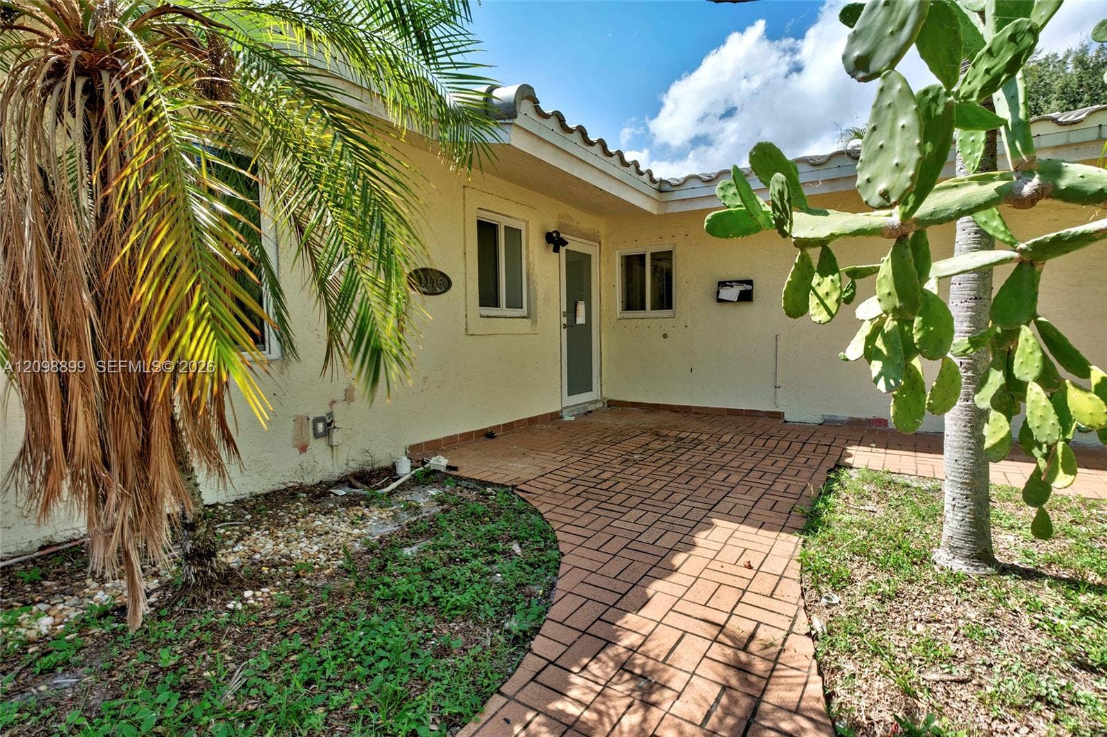 1176 SW 4th Street, Boca Raton, FL 33486 Stucco exterior featuring a tiled roof, brick-paver patio, and mature landscaping