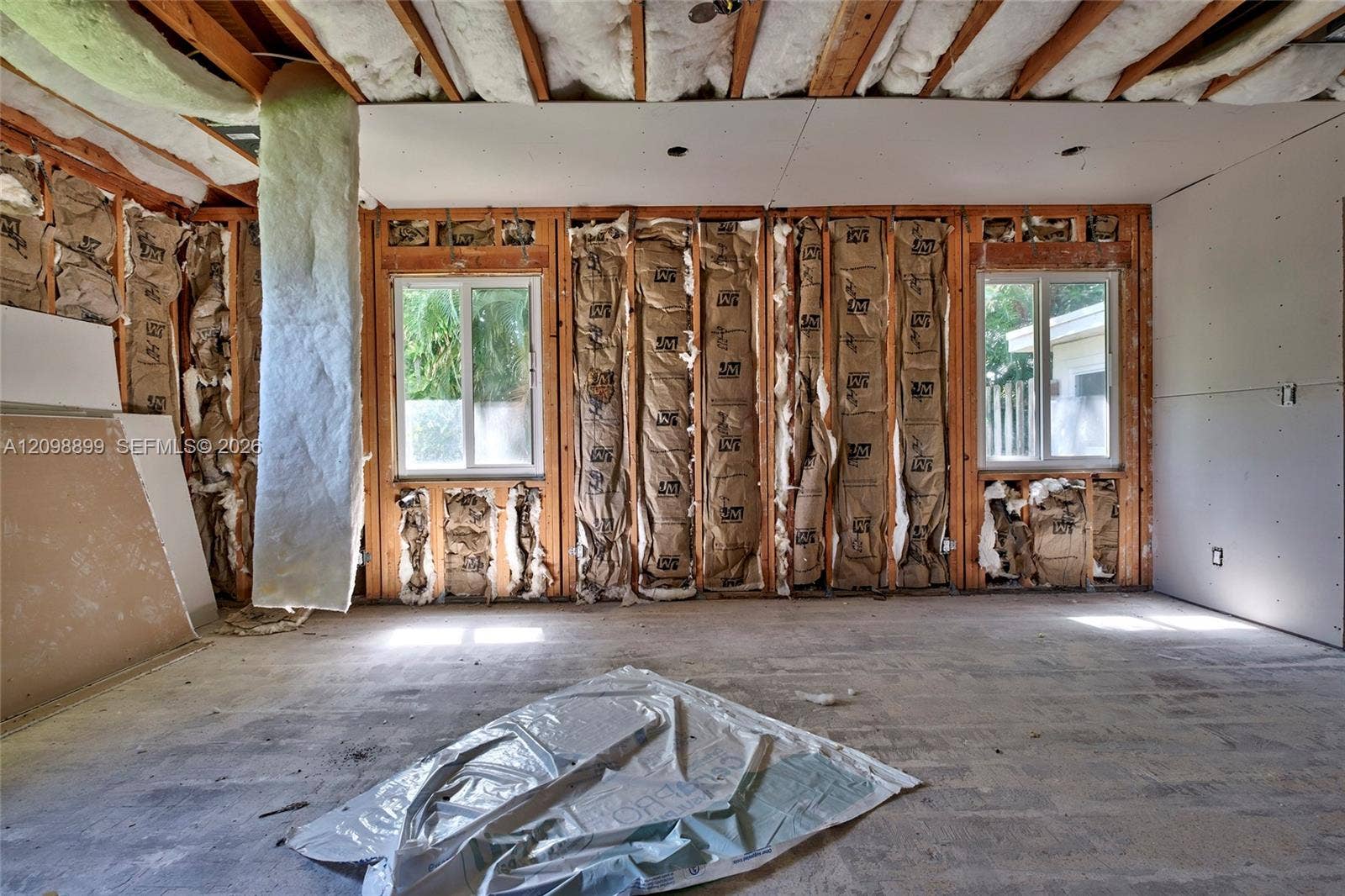 1176 SW 4th Street, Boca Raton, FL 33486 Unfinished interior space featuring exposed wood stud framing, fiberglass batt insulation, concrete flooring, and dual vinyl-framed windows
