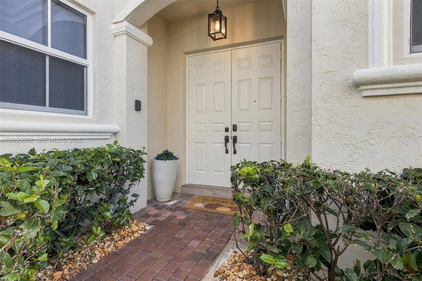1516 Breakwater Terrace, Hollywood, FL 33019 Covered entryway with a brick-paver walkway, double-door entrance, and overhead lantern-style lighting
