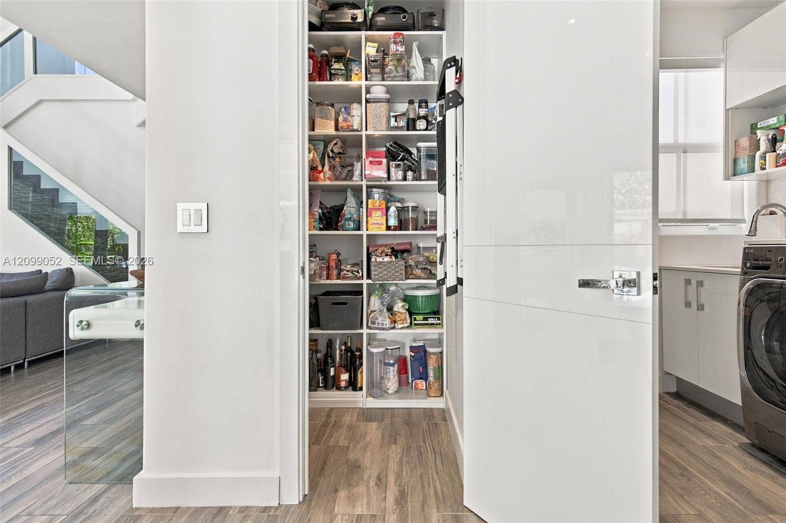 1516 Breakwater Terrace, Hollywood, FL 33019 Walk-in pantry featuring floor-to-ceiling custom white shelving, high-gloss flat-panel door, and wood-finish flooring