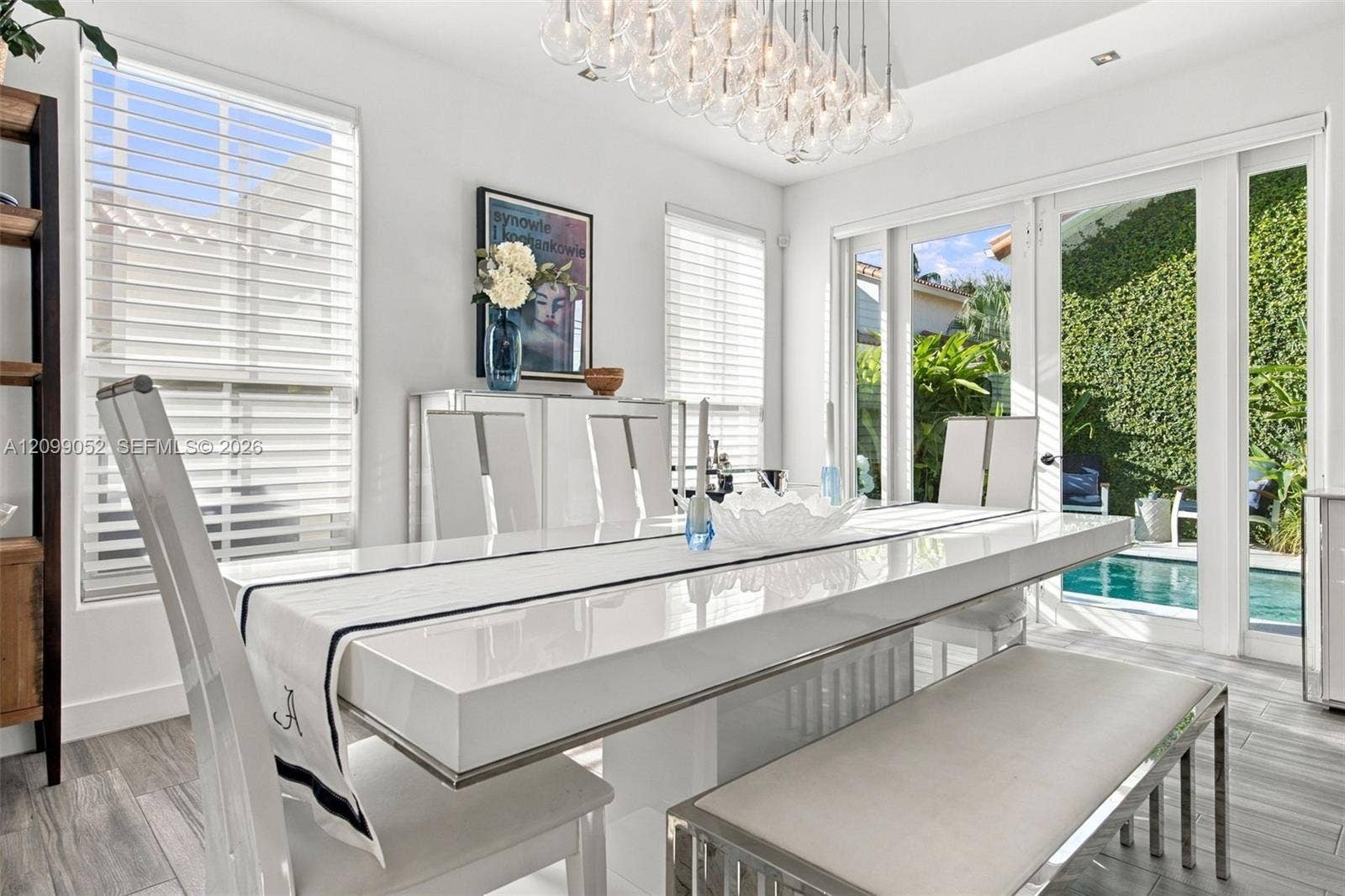 1516 Breakwater Terrace, Hollywood, FL 33019 Dining area featuring large-format tile flooring, multi-globe chandelier, crisp white walls, horizontal window blinds, and glass doors opening to an outdoor swimming pool area
