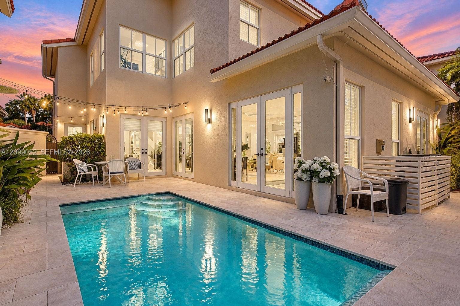 1516 Breakwater Terrace, Hollywood, FL 33019 Stucco exterior featuring multiple sets of glass-paneled double doors, stone-tiled patio, and a built-in swimming pool