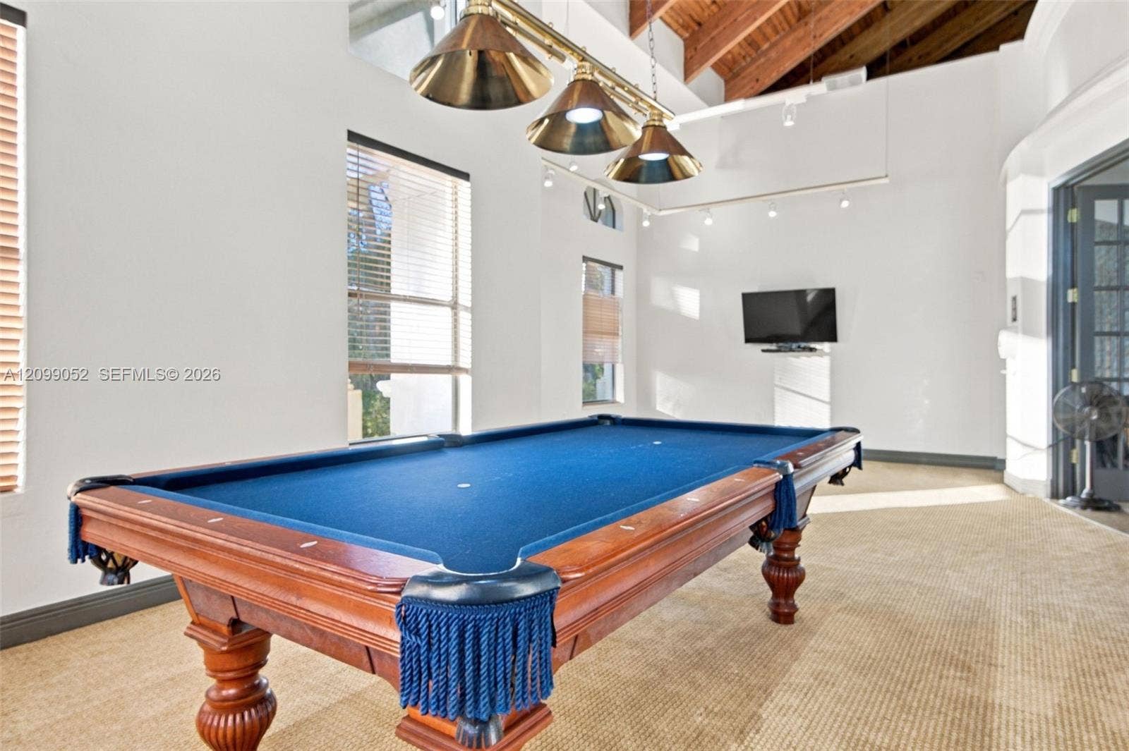 1516 Breakwater Terrace, Hollywood, FL 33019 Vaulted ceiling with exposed wood beams, triple-pendant brass lighting fixture, and multiple tall windows