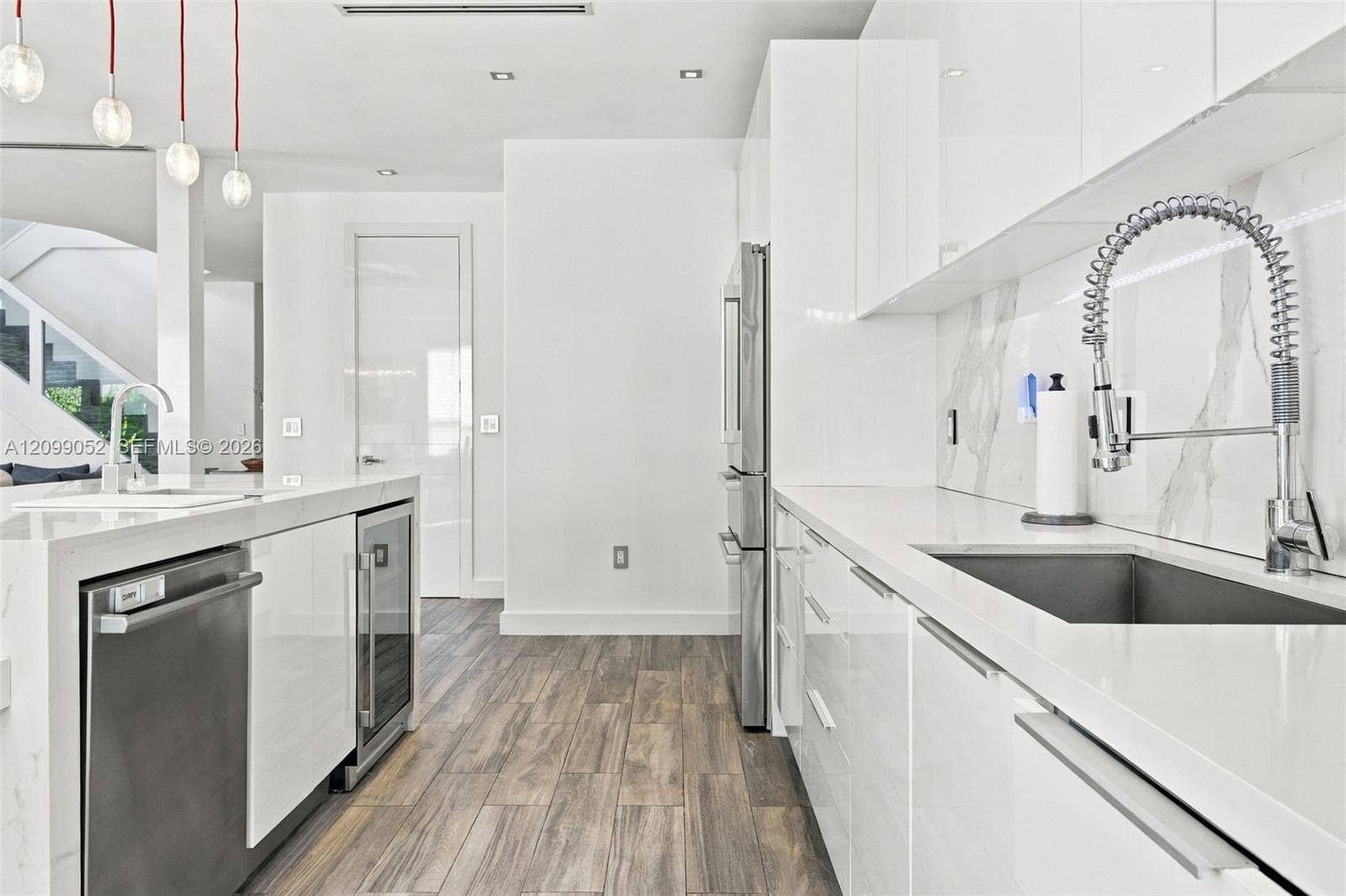 1516 Breakwater Terrace, Hollywood, FL 33019 Kitchen featuring high-gloss white cabinetry, white stone countertops, integrated stainless steel appliances, a pull-down commercial-style faucet, and wood-finish flooring