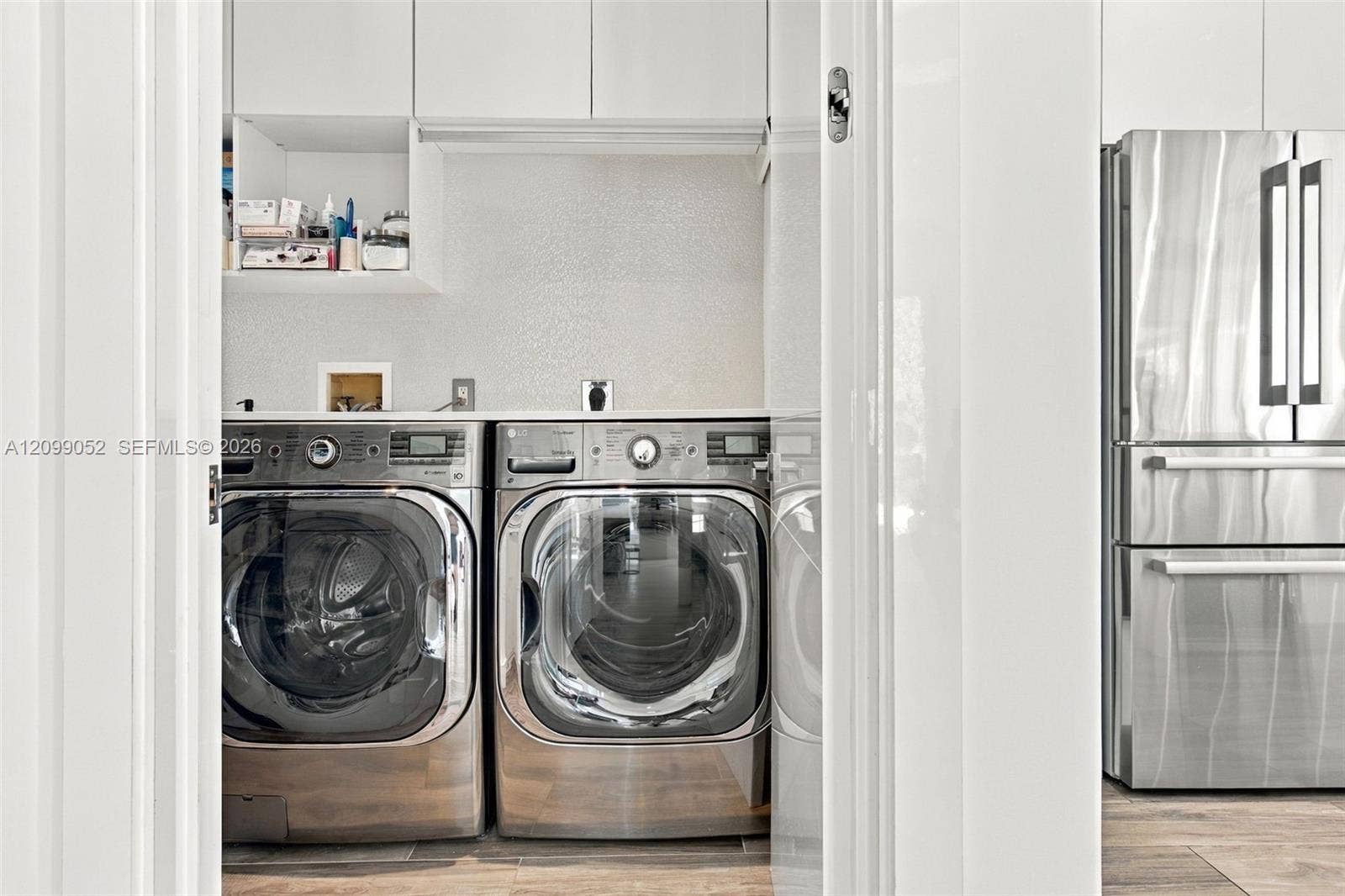 1516 Breakwater Terrace, Hollywood, FL 33019 Laundry area featuring white cabinetry, custom shelving, a solid-surface countertop, and stainless steel appliances